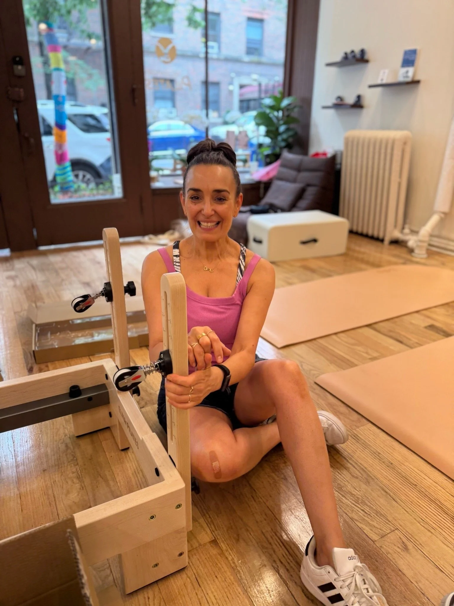 A smiling expert at Hell's Kitchen Pilates preparing an Elina Pilates reformer for delivery and setup in the NYC showroom.