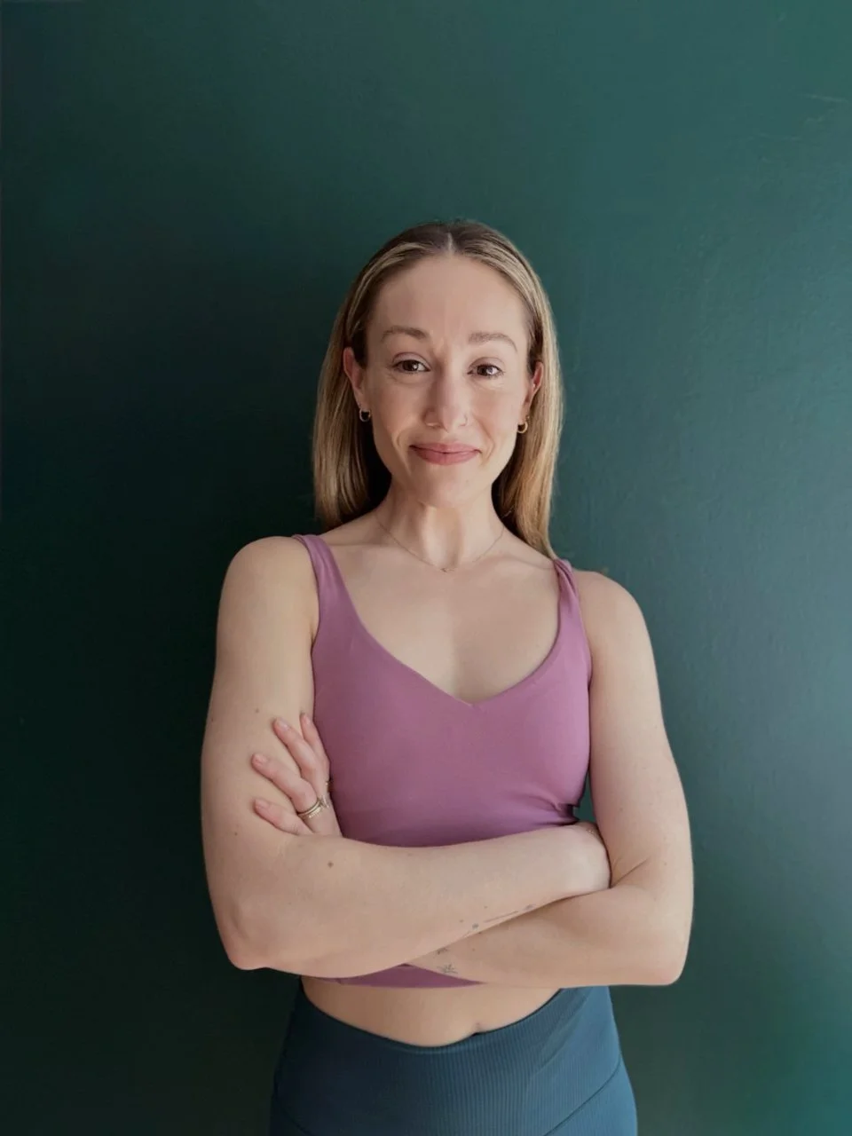 Rachel Peterson, Pilates instructor at Hell's Kitchen Pilates, standing with arms crossed in the studio.
