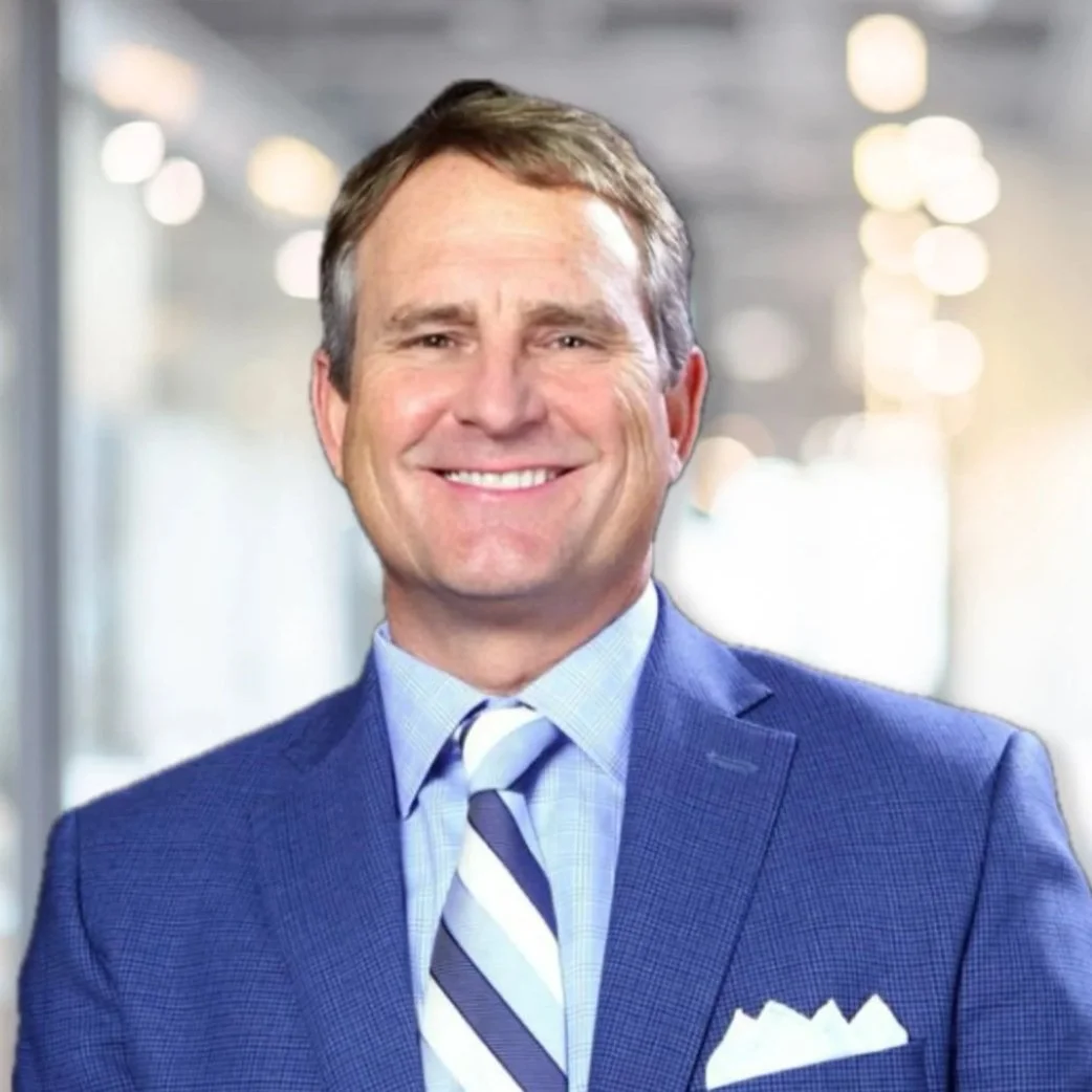 A smiling man in a suit, wearing a tie.