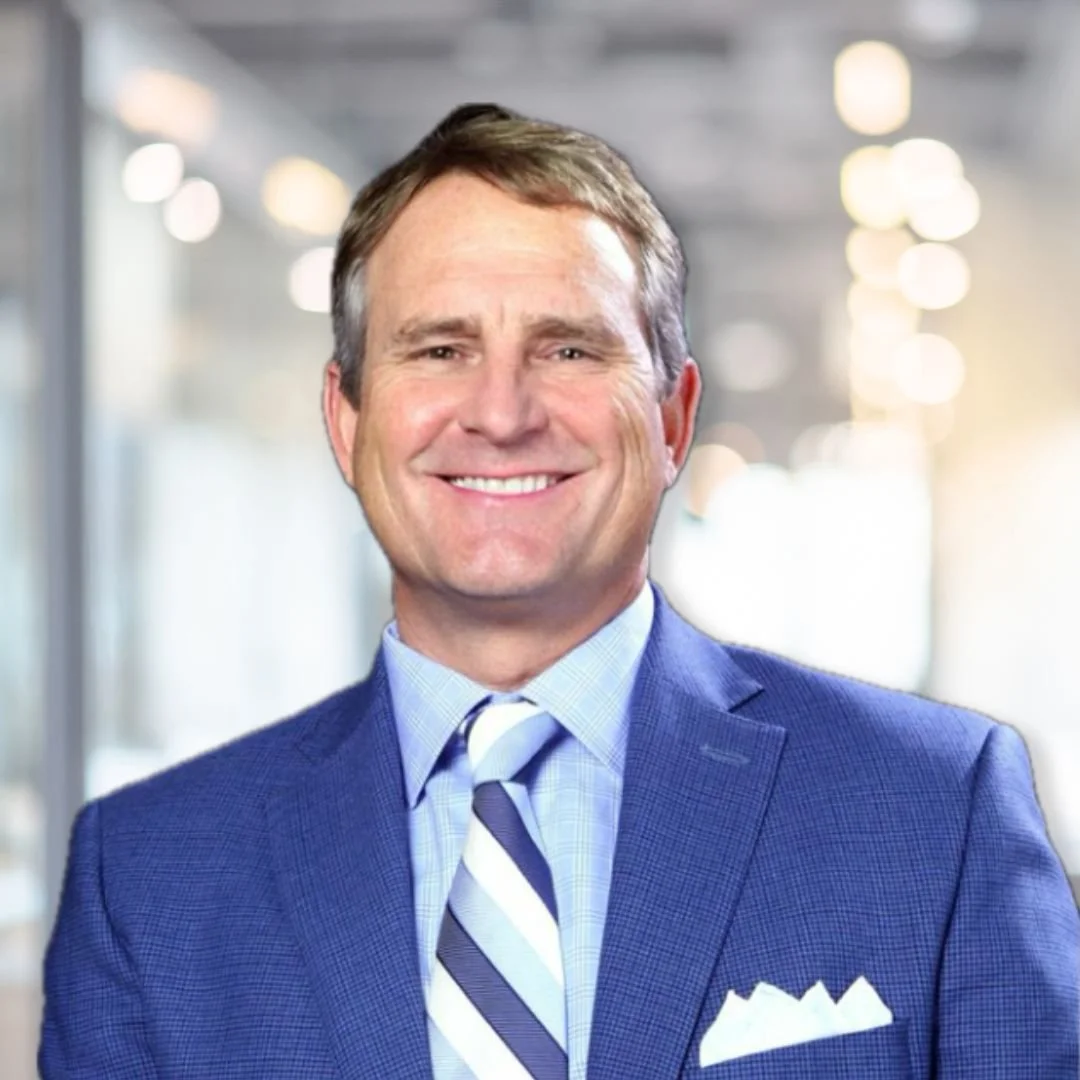 A smiling man in a suit, wearing a tie.