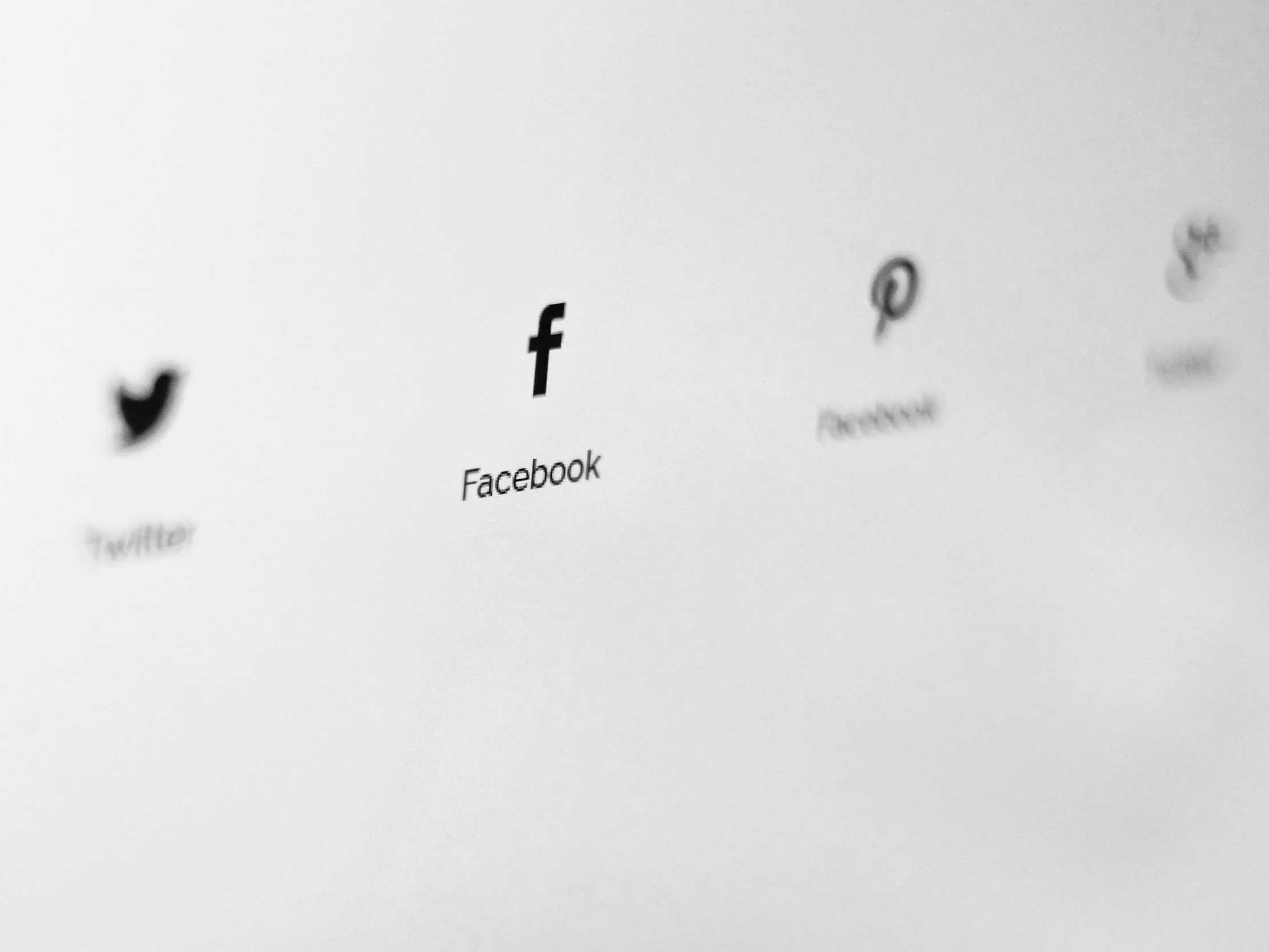 Black social media icons blurred on white background