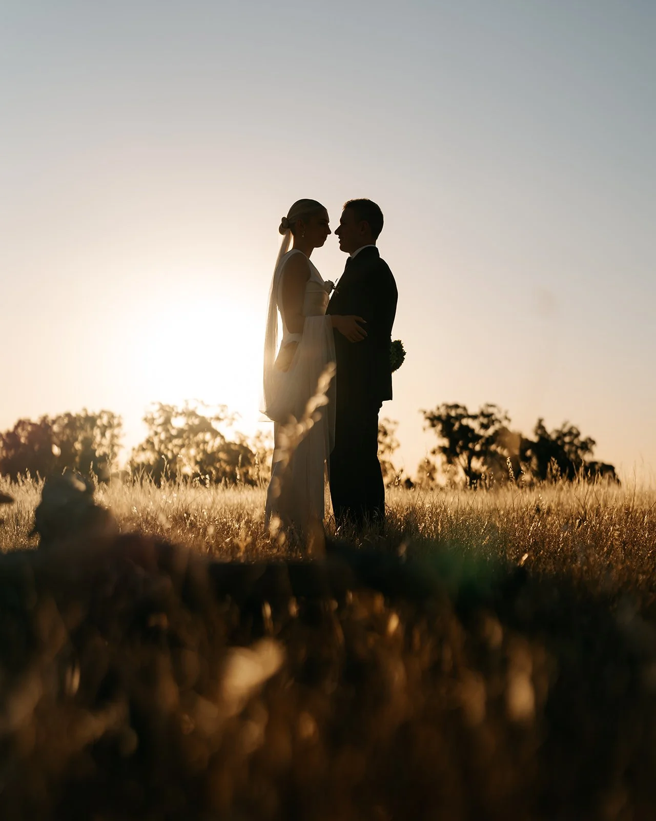 Bride and groom silhouetted against a beautiful country sunset in a pasture paddock at Rawson Park Homestead near Wagga Wagga, NSW.