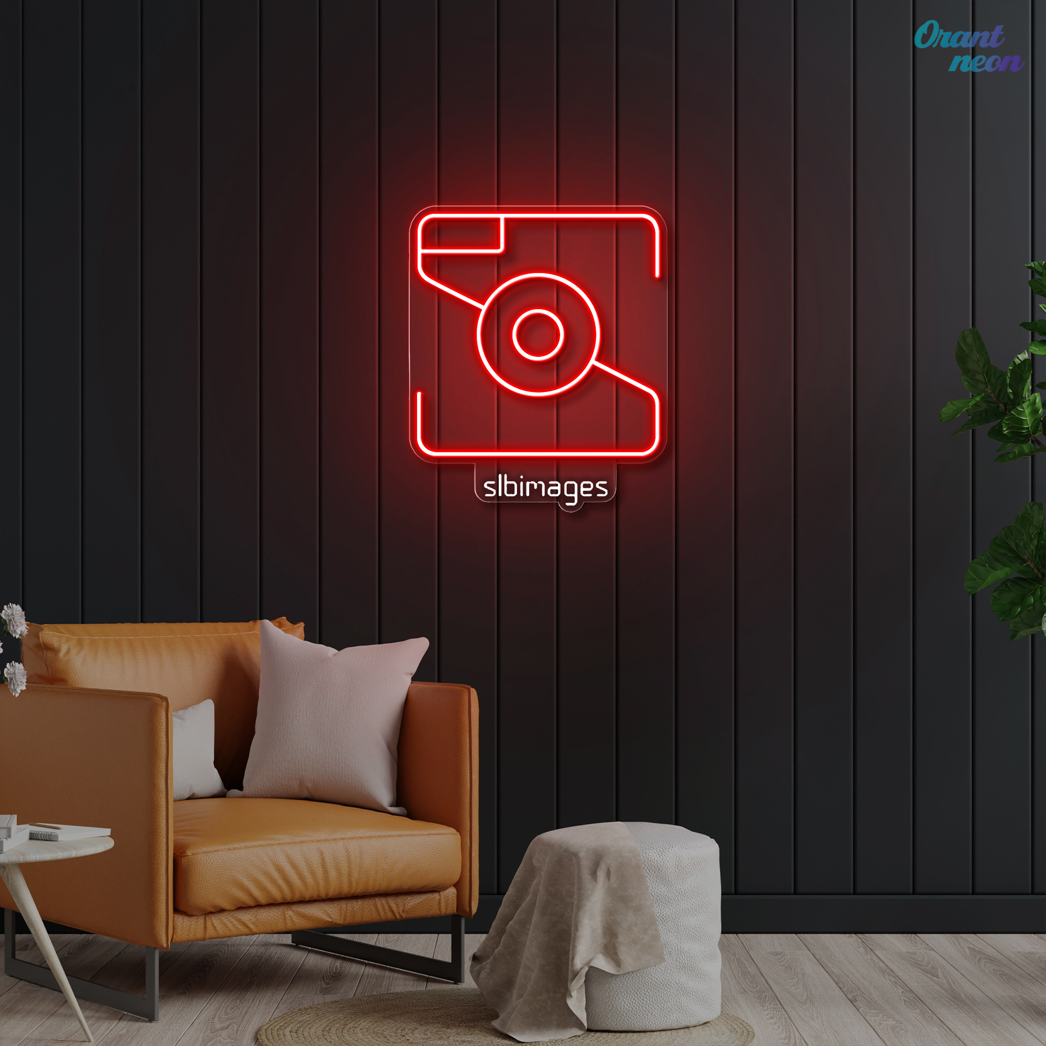 Neon sign of a camera and the text 'slbimages' on a black wall in a modern living room with an orange sofa, white pillows, a small white side table, and a leafy plant.