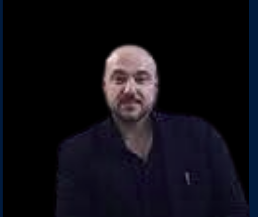 Uomo con cappotto nero su sfondo scuro.