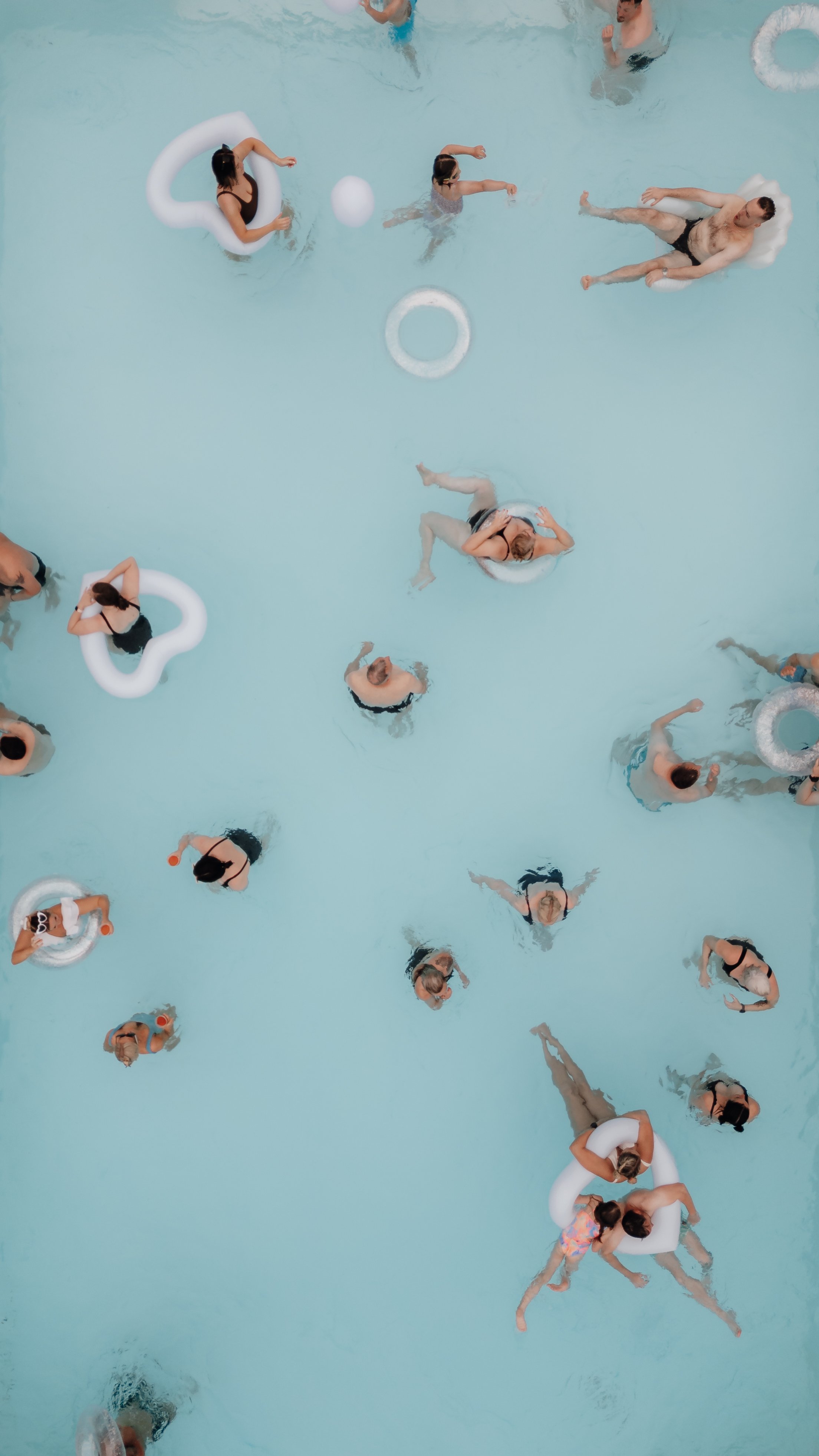 Top-down view of people swimming and floating on inflatables in a pool at a destination wedding.