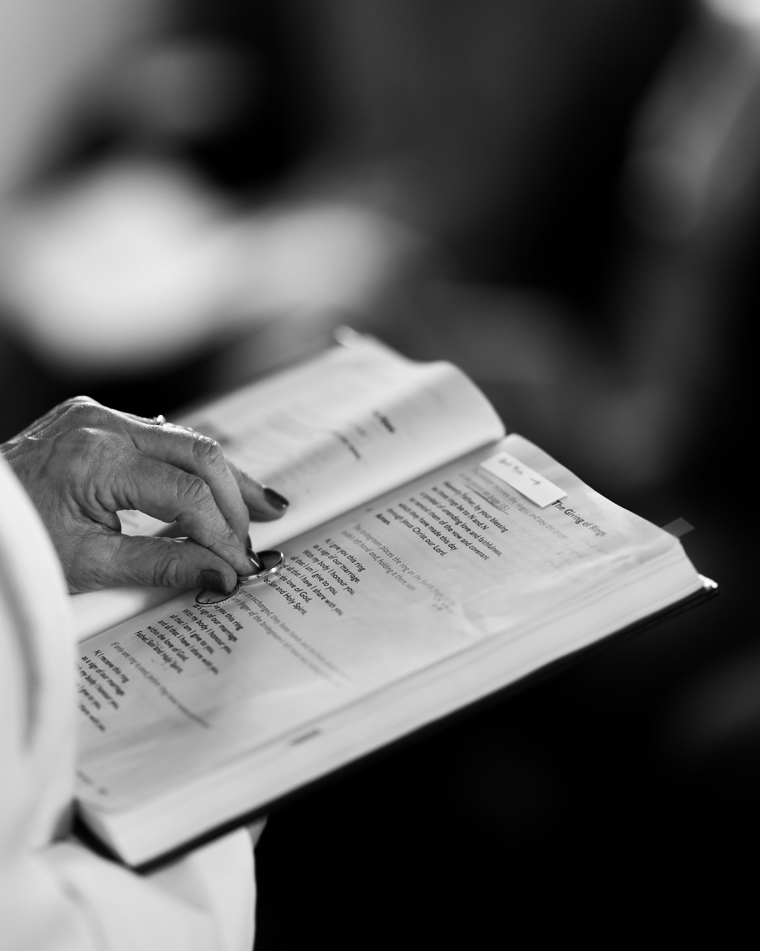 Black and white photo of a person holding an open book or hymnal, with visible text on the pages.