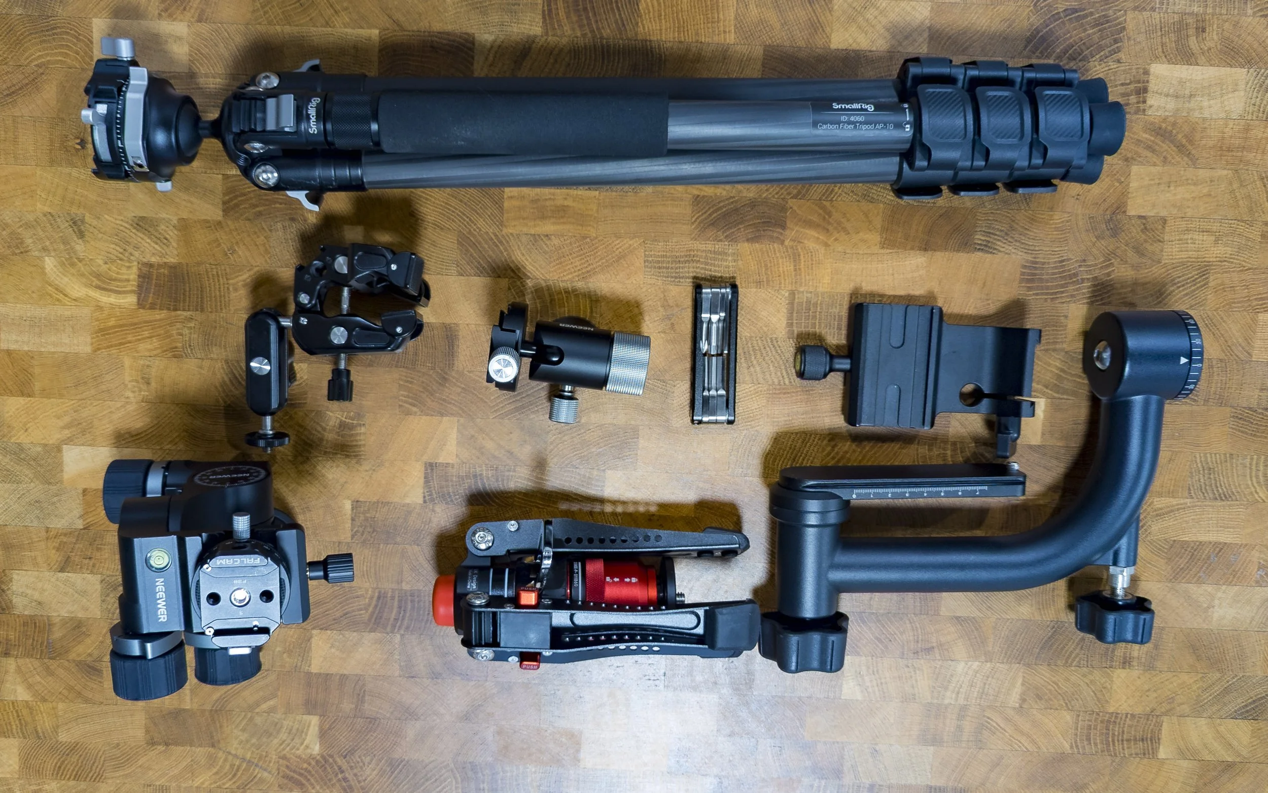 A collection of camera and photography equipment neatly arranged, including a large tripod, camera mounts, clips, and various camera accessories.