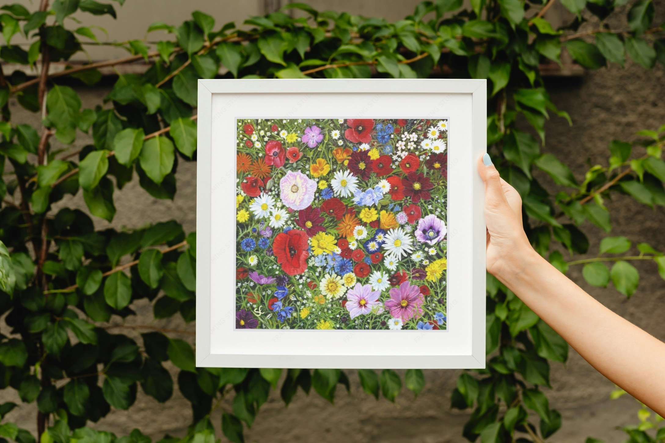 Wildflowers framed print being held against foliage