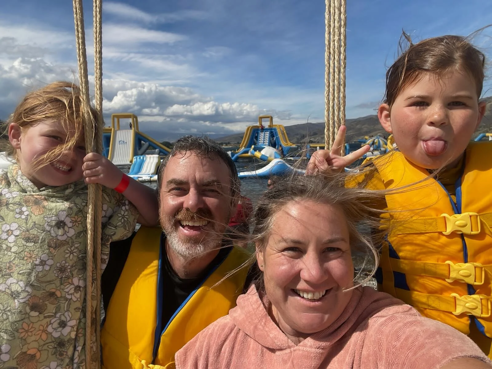 Photograph of Kev, co-founder of Adult Proof, with his family and two children at an activity park at sea wearing lifejackets