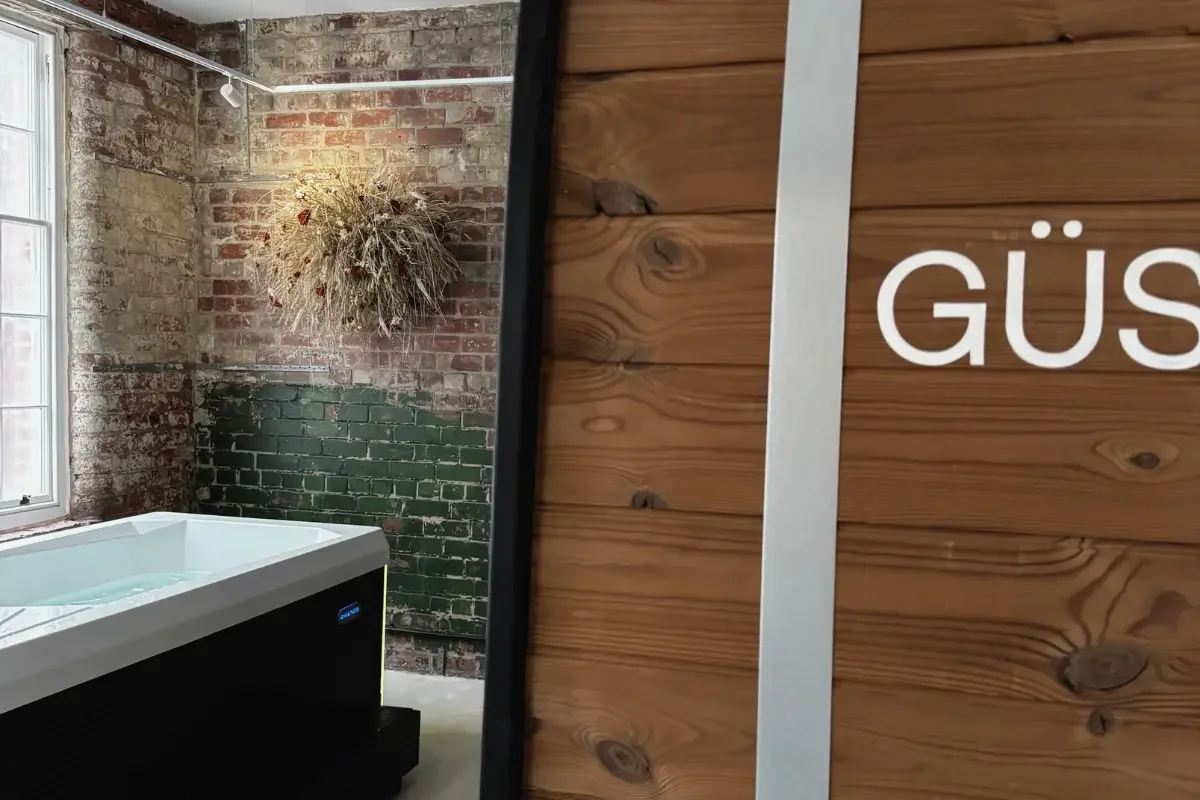 Close up of Güs sauna with Anther dried grass installation and cold plunge in the background