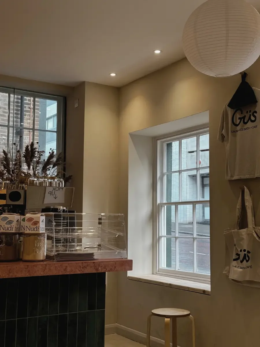 Quiet corner of Güs Sheffield coffee bar with stools and window views with Anther floral installation
