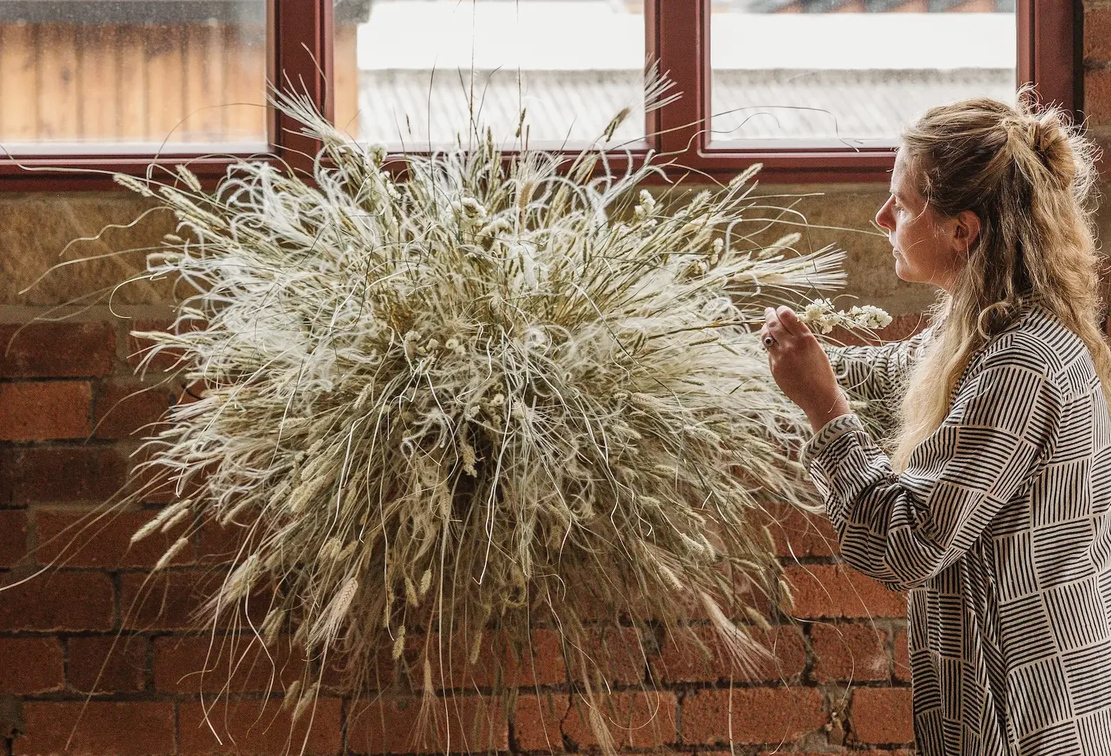 Jess at Anther creating a dried flower and grasses wall hanging in Sheffield events space