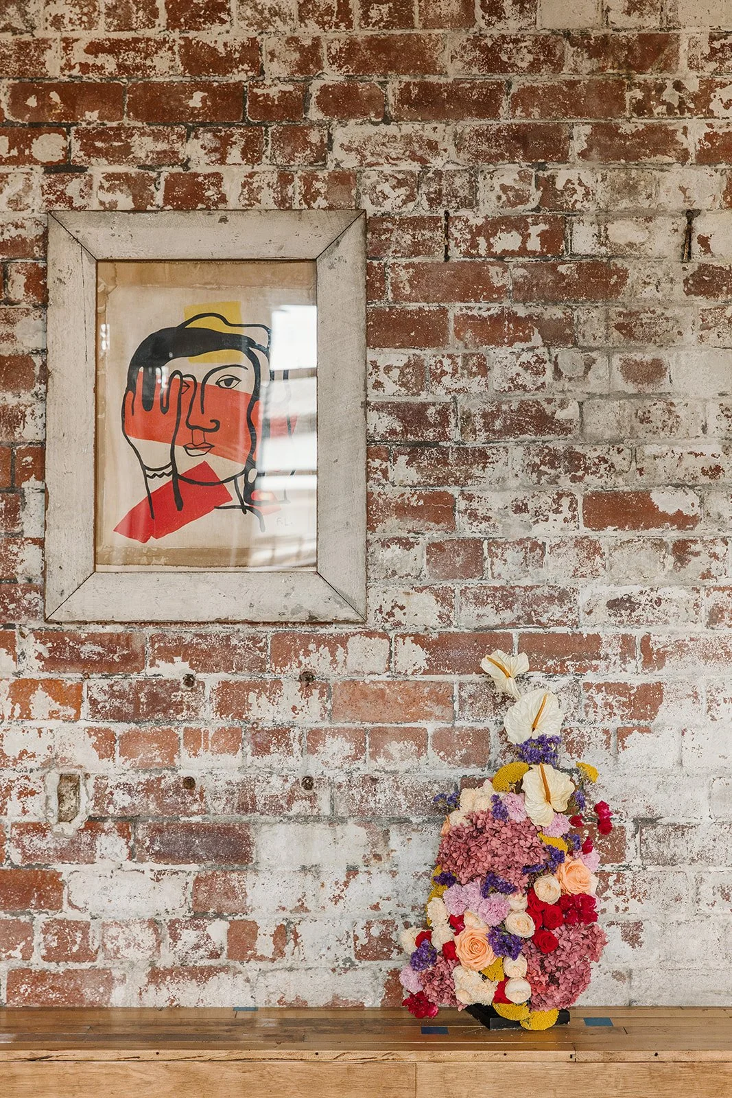 Colourful everlasting floral centrepiece with abstract picture and rustic brick background