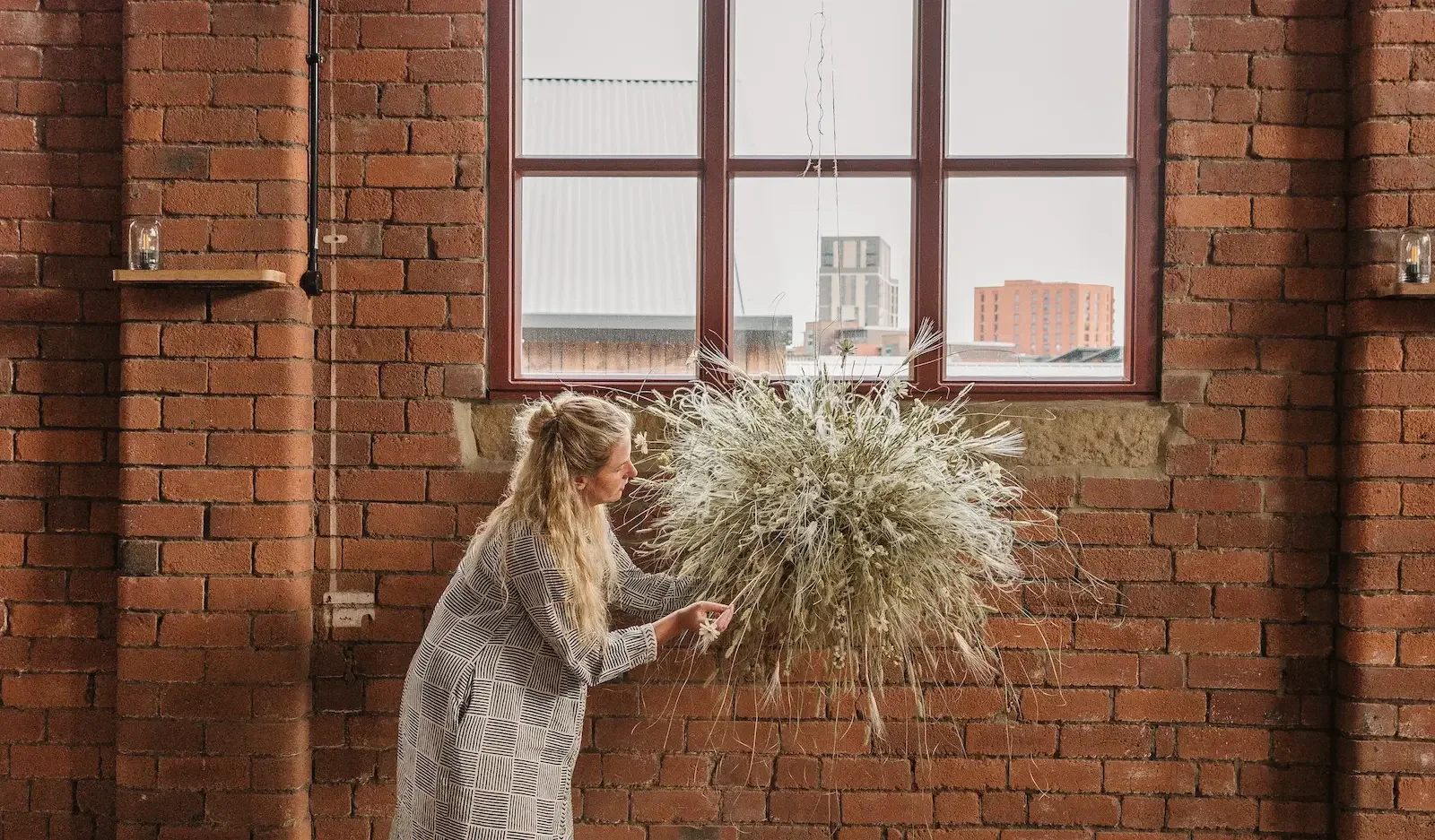 Jess owner and creator at Anther sculpting a dried grasses suspended hanging