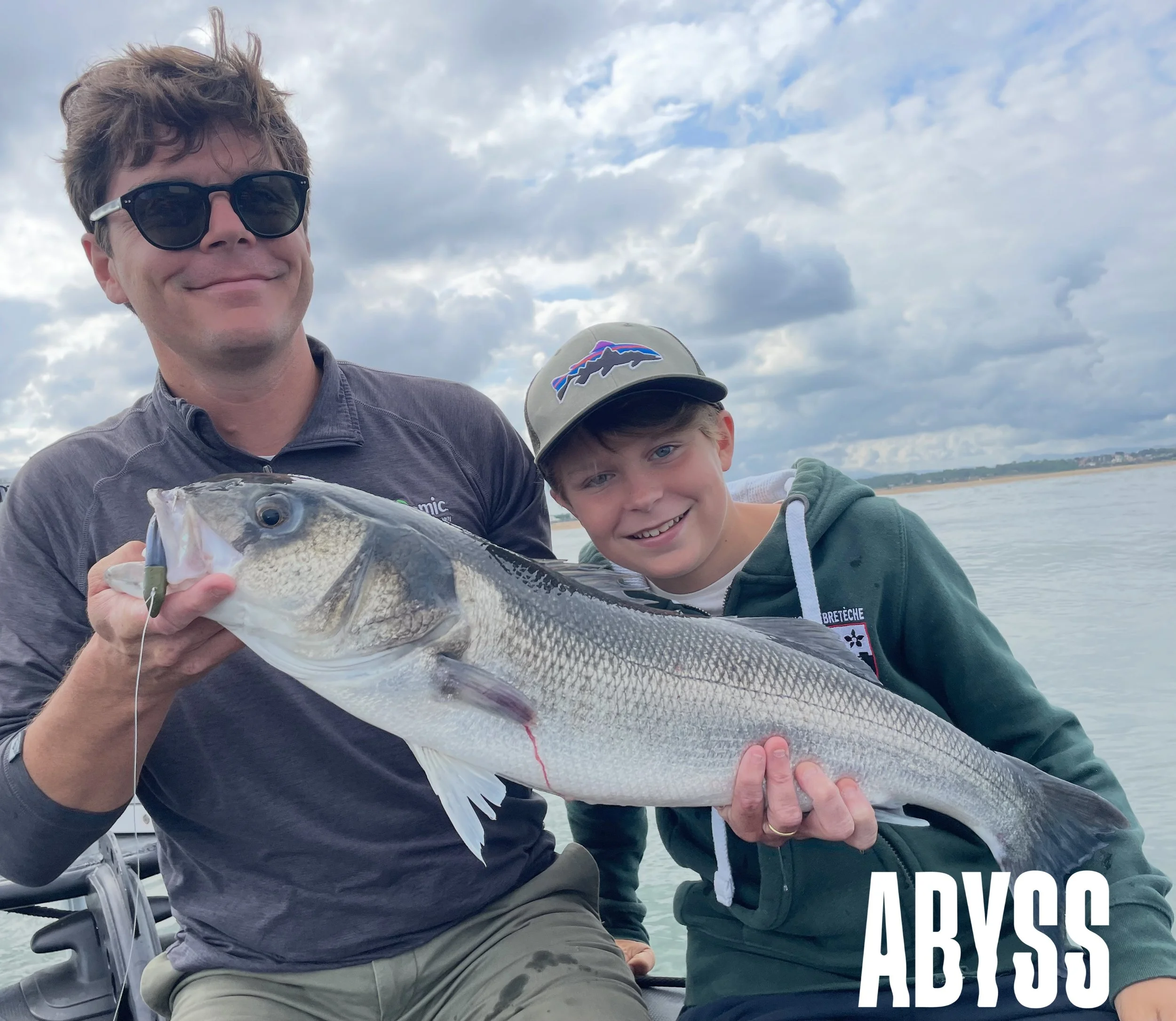 un pere et son fils avec unn bar, un loup de mer, une louvine trophée devant les passes de bayonne a la sortie de l'adour