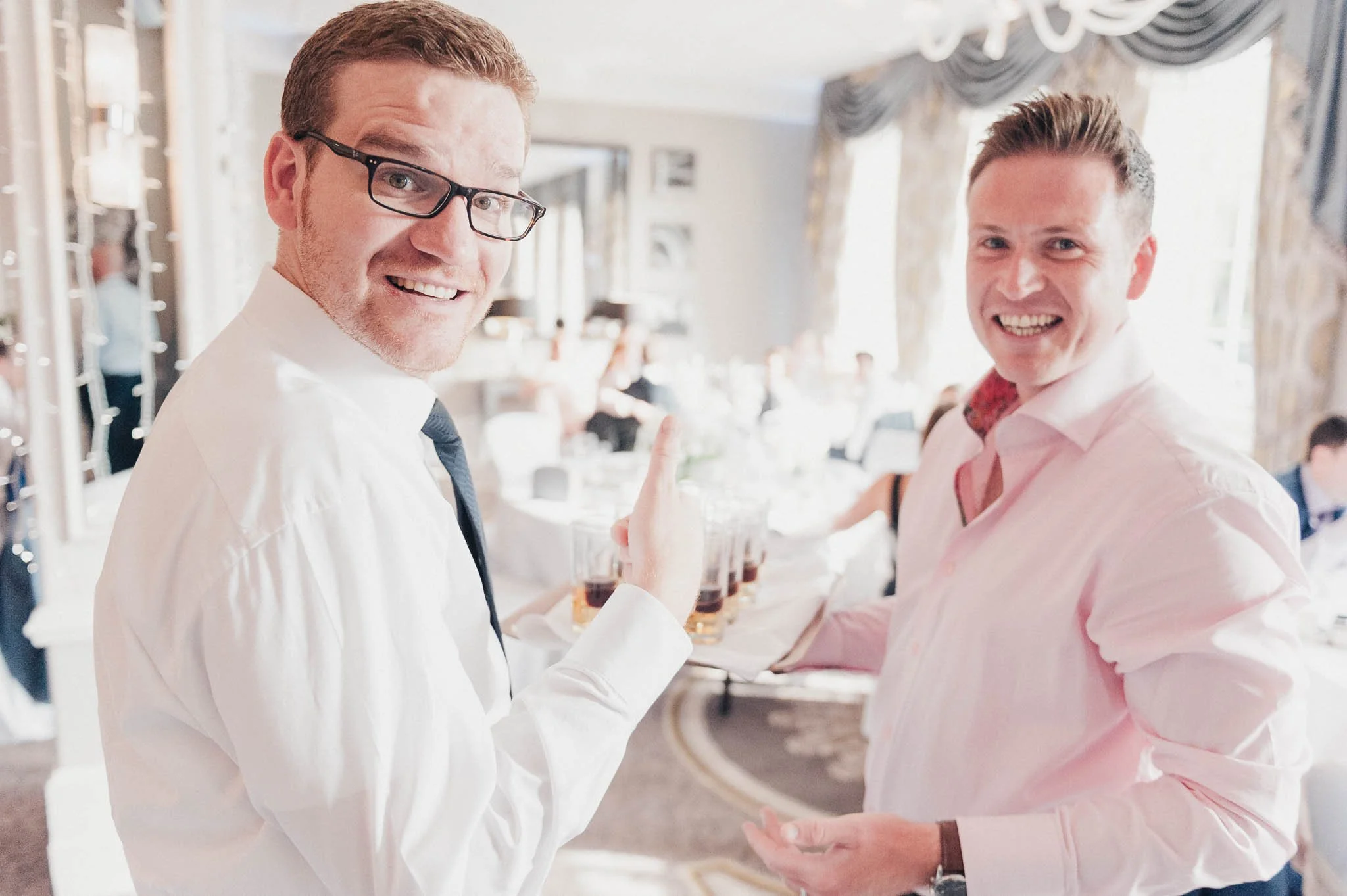 Two guests smiling toward the camera while holding drinks during the reception.