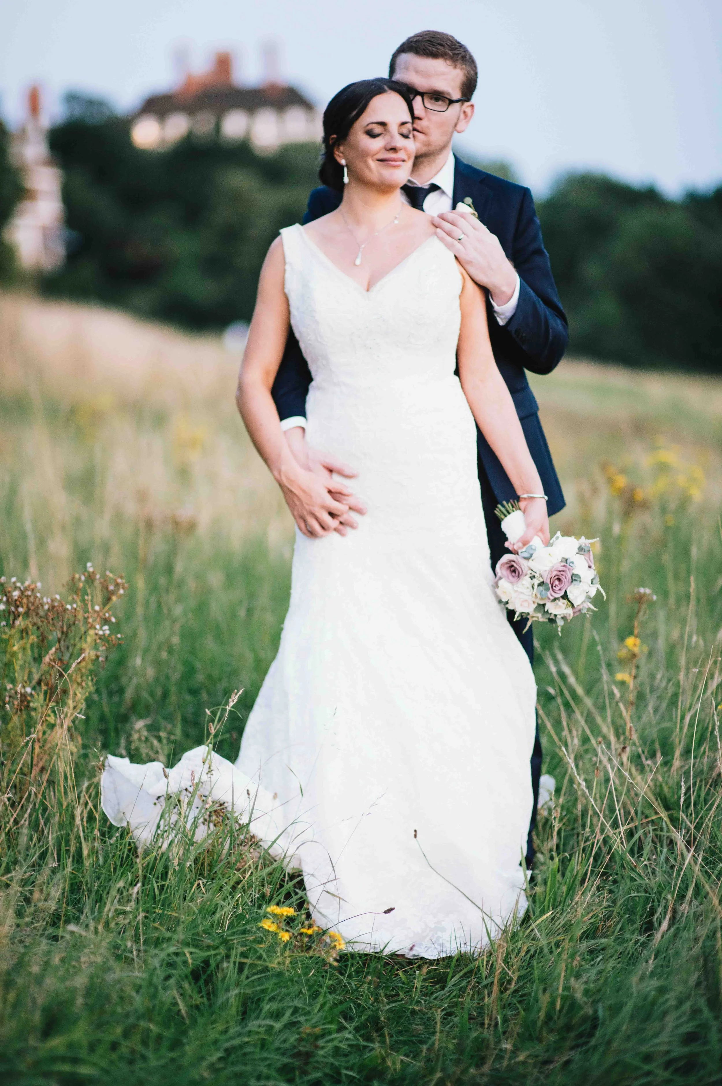 Bride and groom standing together in a countryside field during their wedding portraits in France.