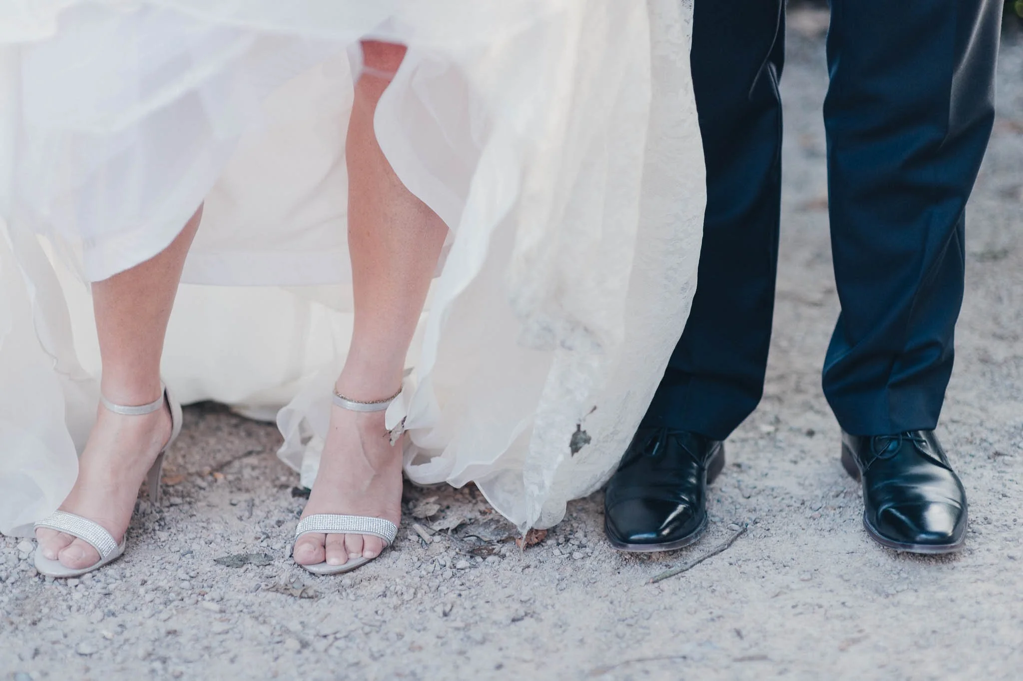 Close-up of the bride lifting her dress to reveal her shoes as the couple walk together.