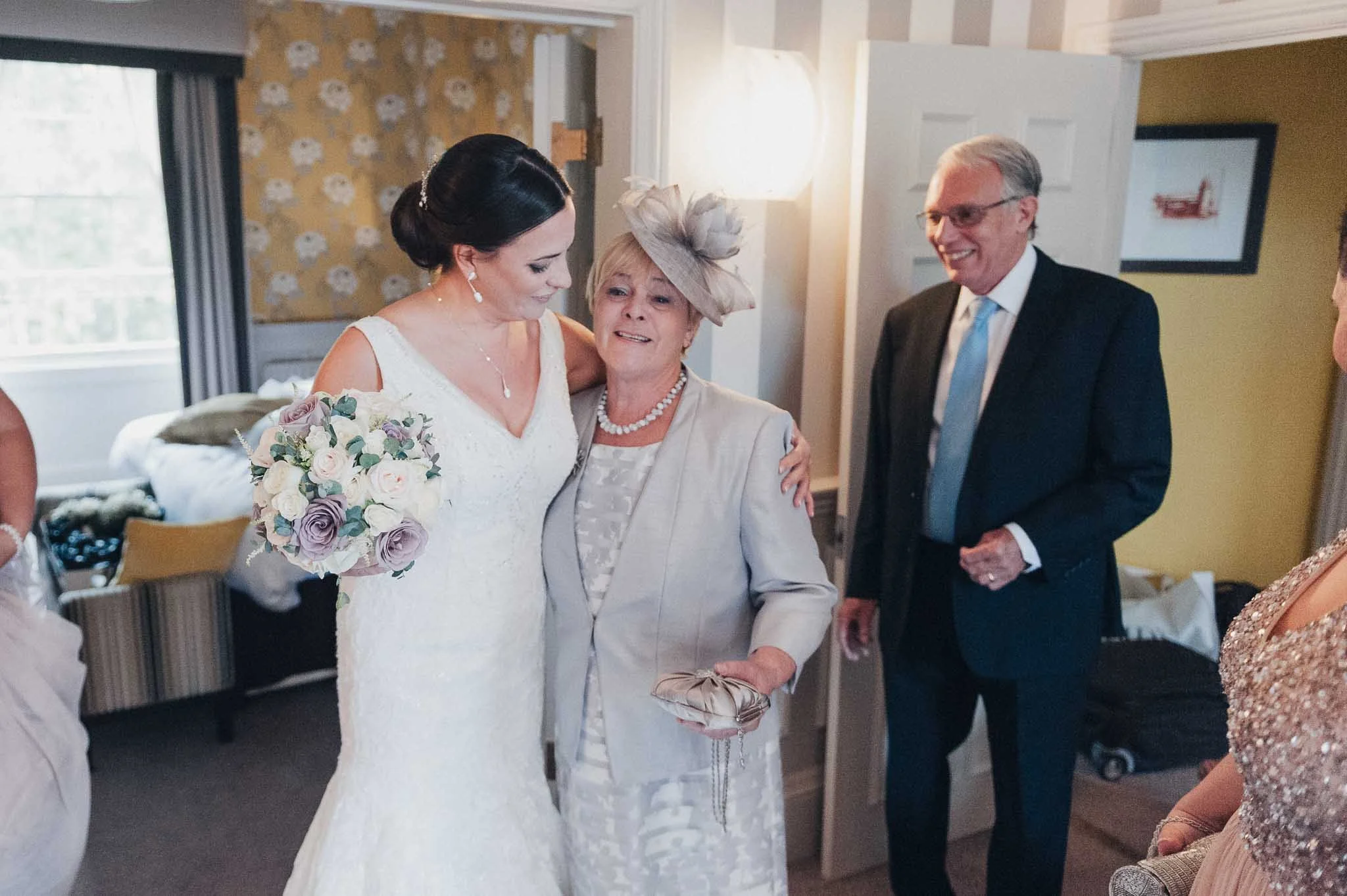 Bride sharing an emotional moment with a family member while holding her bouquet on the wedding morning.