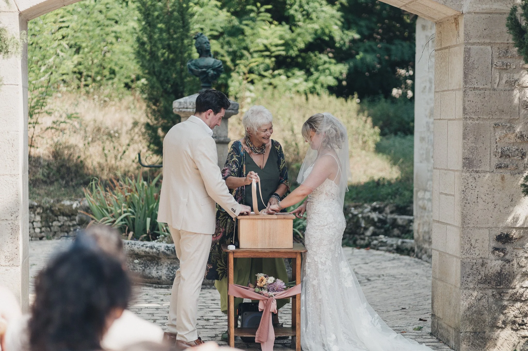 Couple and celebrant taking part in a symbolic moment during the outdoor ceremony