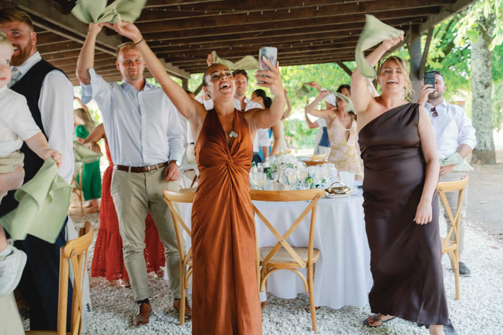 Wedding guests celebrating and waving napkins at an outdoor reception in Southwest France