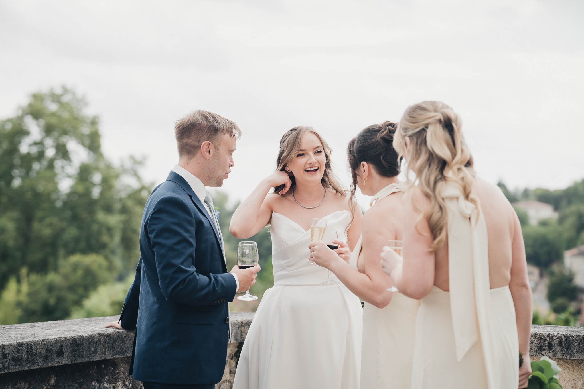 Bride, groom and close friends talking and holding drinks during the reception at Manoir de Longeveau.