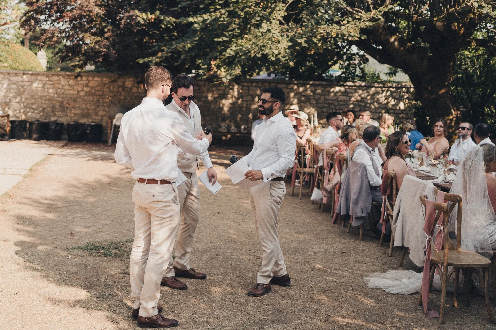 Groomsmen preparing speech notes during the outdoor wedding reception in the Dordogne.