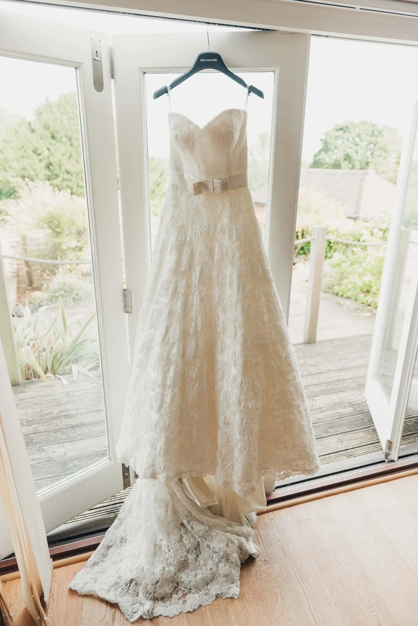 The bride’s lace wedding dress hanging in the doorway before she gets dressed.