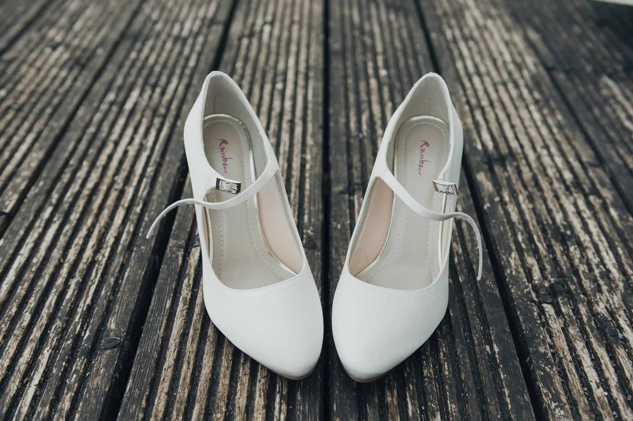 The bride’s white wedding shoes placed on wooden decking before the ceremony.