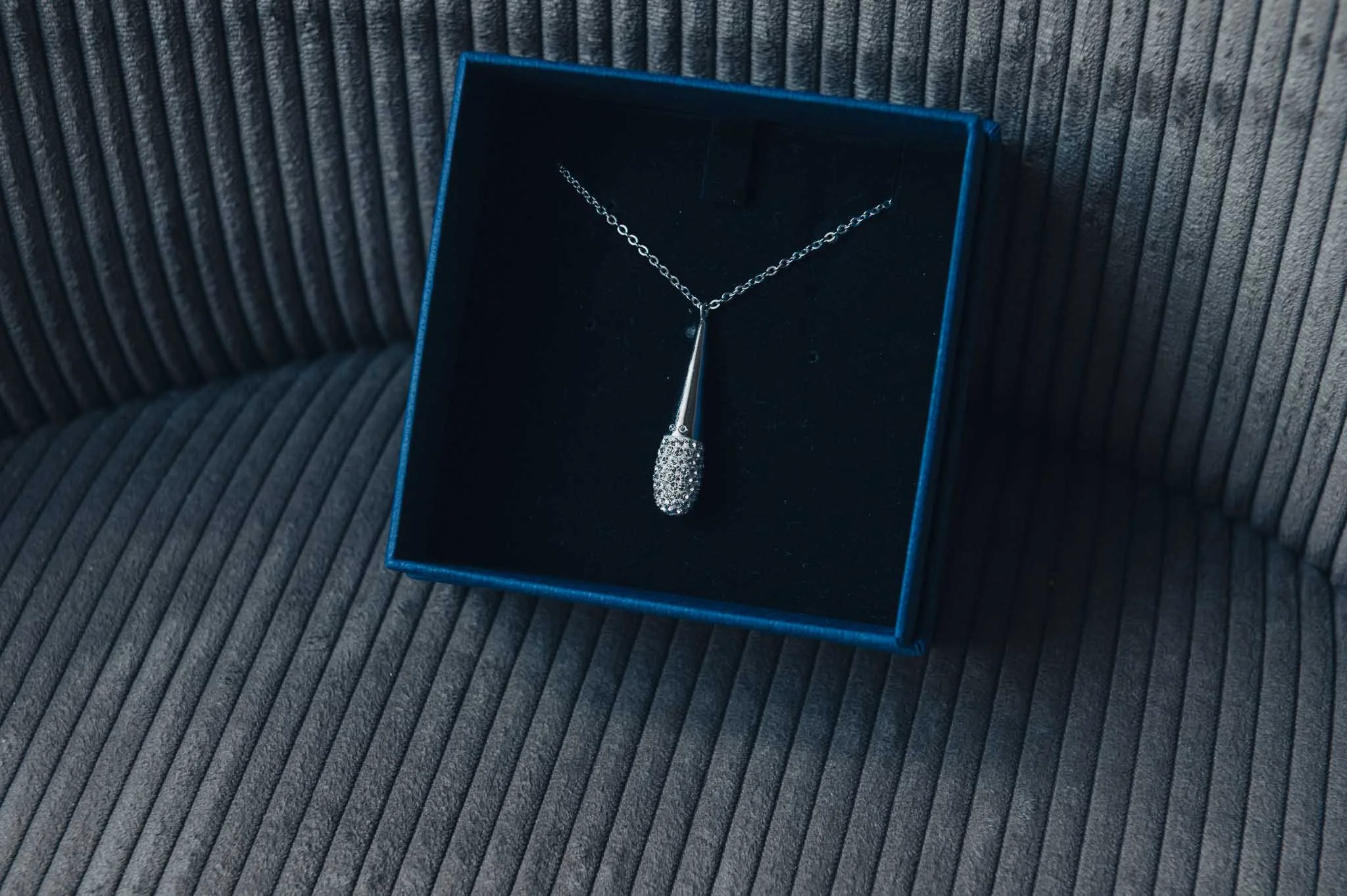 A close-up of the bride’s necklace displayed in a blue presentation box.