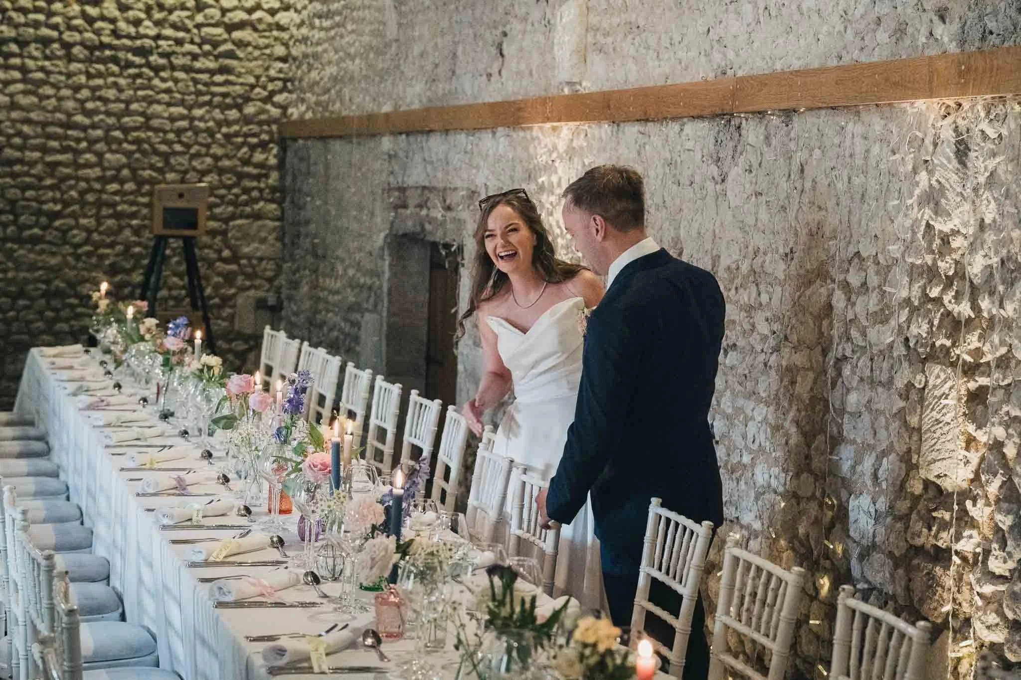 Bride and groom walking along the long reception table set for dinner at Manoir de Longeveau.