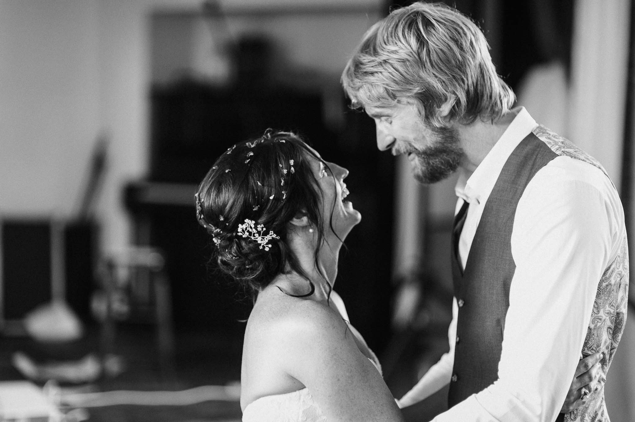 Black-and-white close-up of the bride and groom smiling at each other during their first dance.