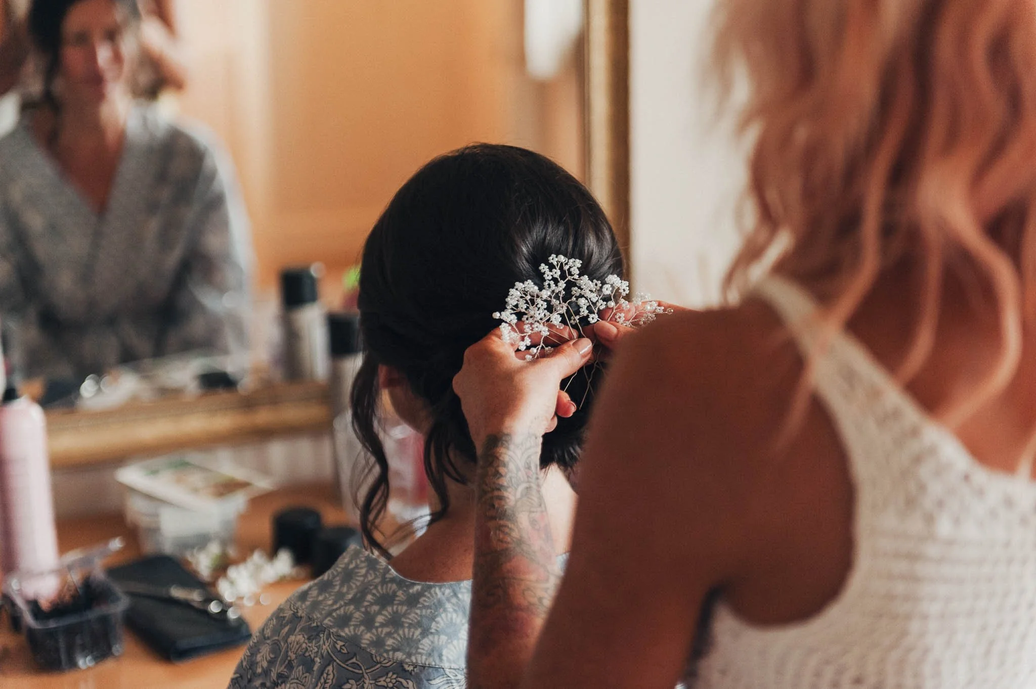 Hair stylist placing a decorative hairpiece into the bride’s hair before the reception.