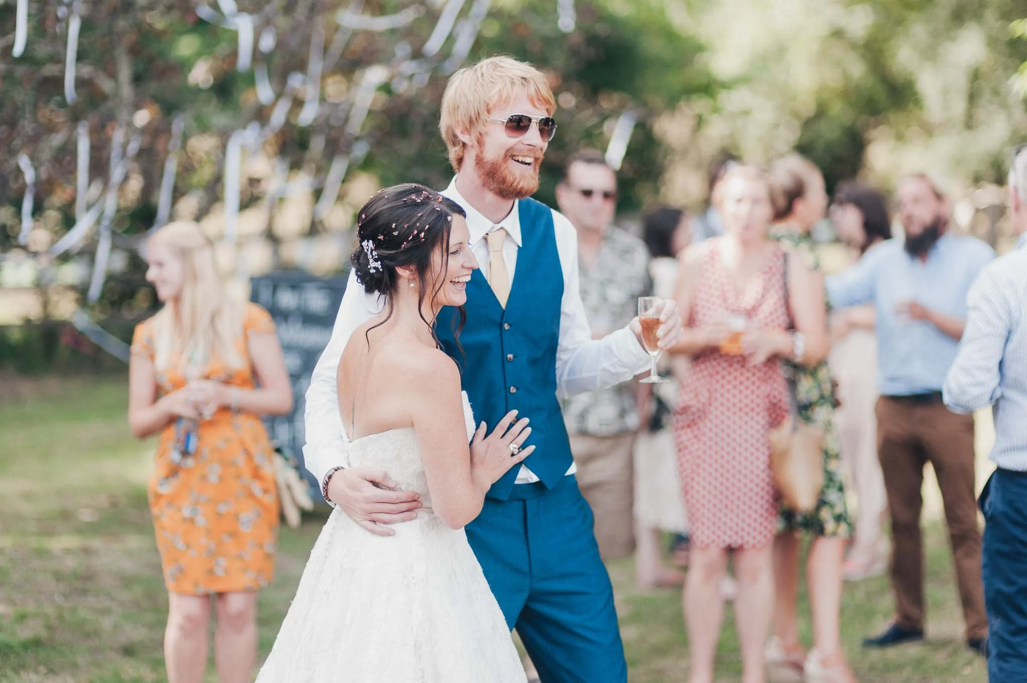 The bride and groom dancing together during the outdoor reception while guests look on.