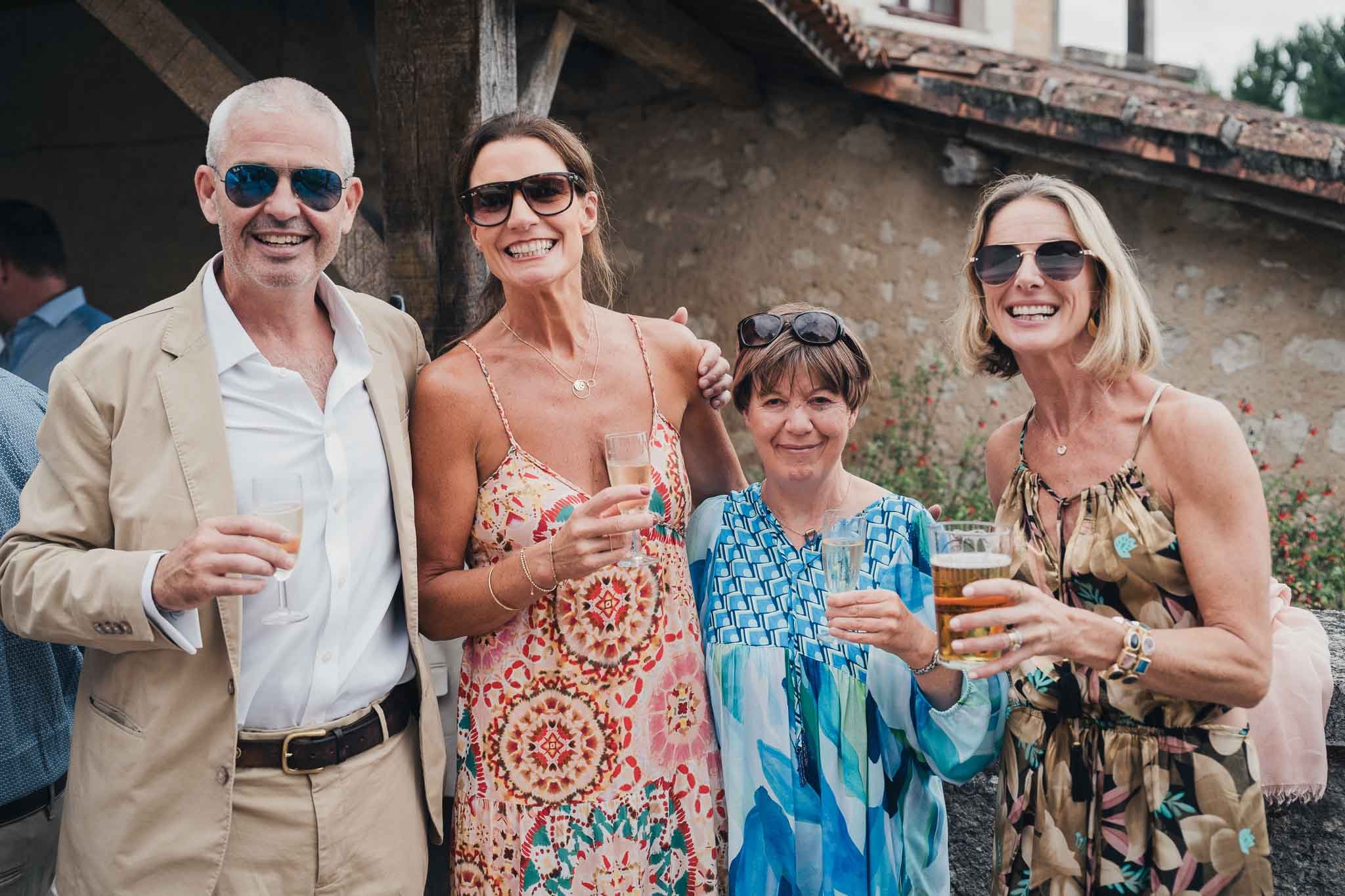 Three guests smiling for a photo during the outdoor drinks reception at Manoir de Longeveau.