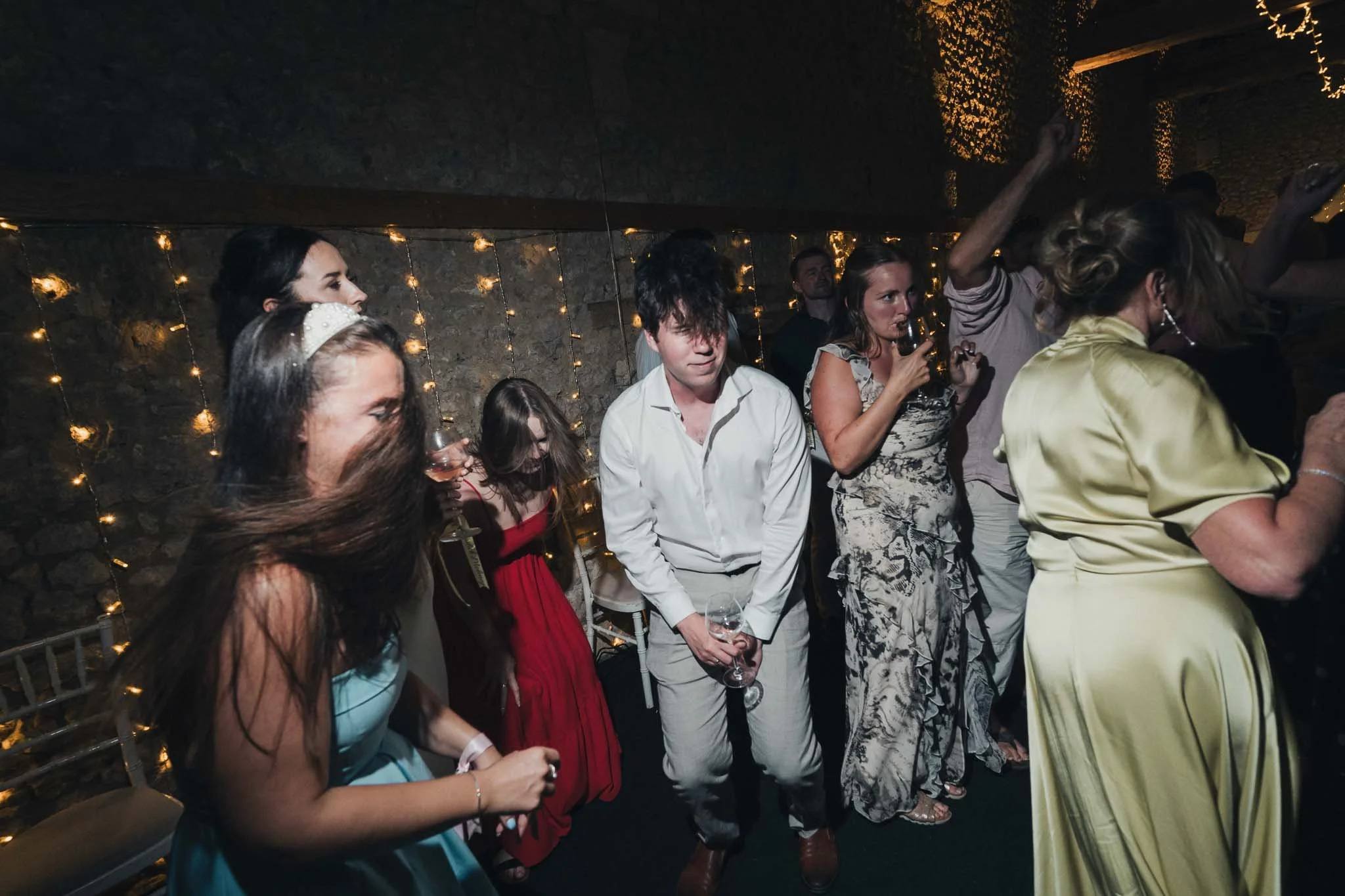 Guests dancing and celebrating under string lights inside the barn.