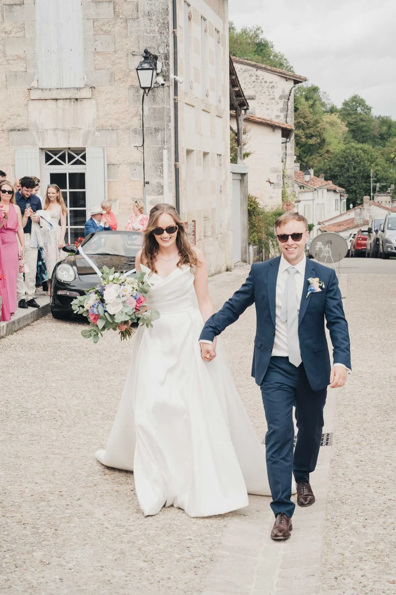 Bride and groom walking hand-in-hand through the village streets after the ceremony.