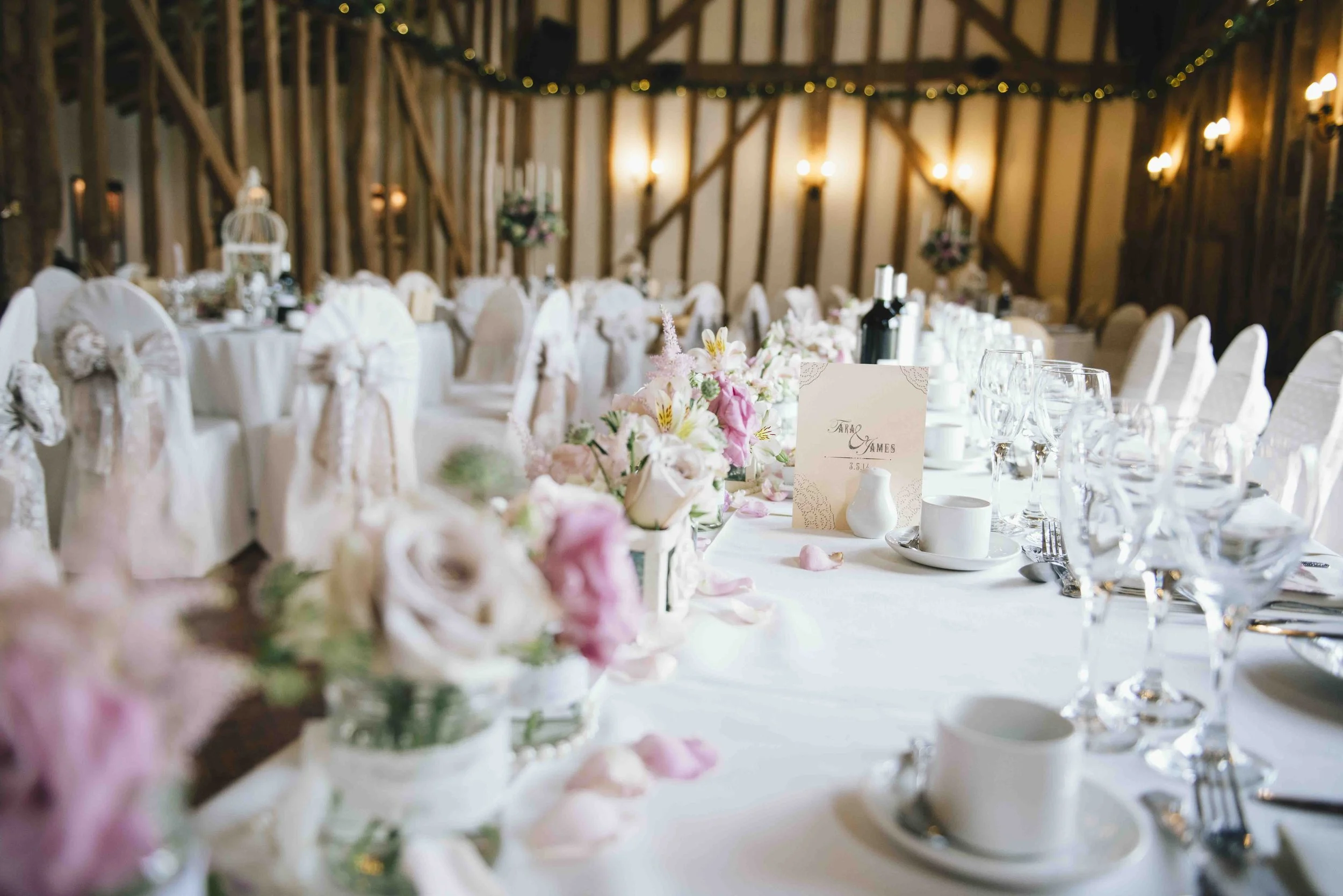 Wedding reception table at a French château with white linens, pastel flowers and crystal glassware