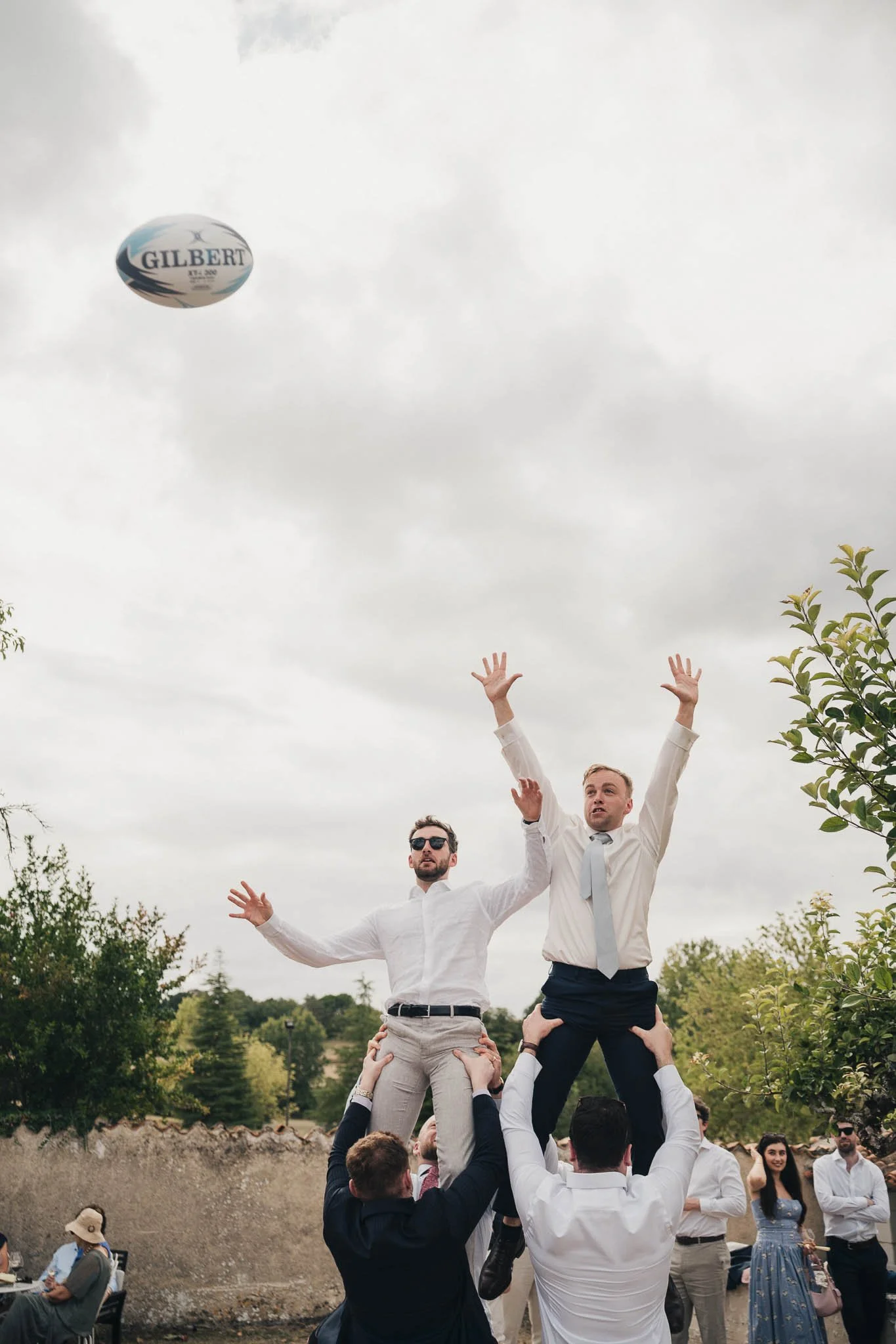 Groom and groomsmen jumping in the air for a line out in the venue grounds.