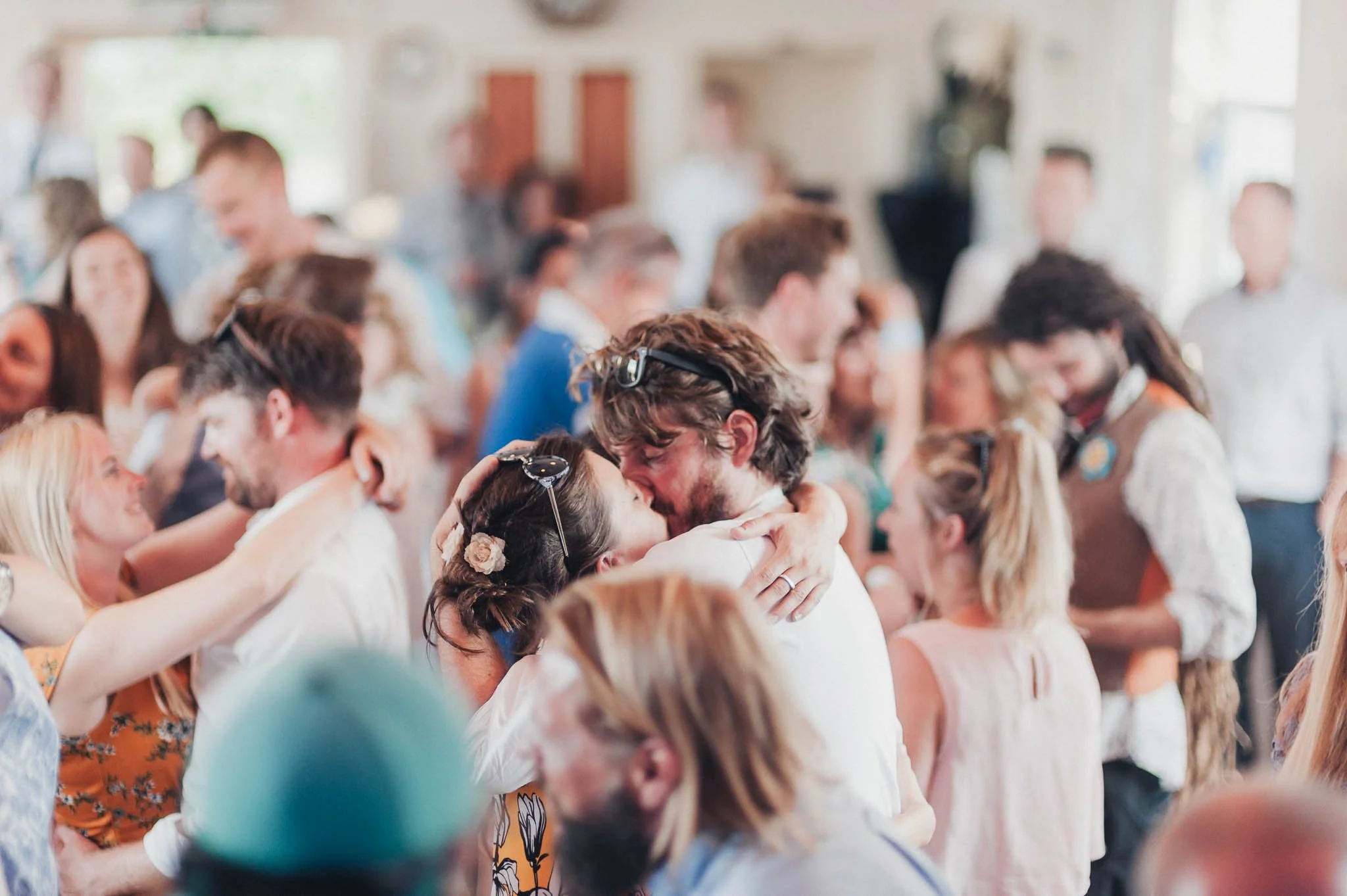Guests laughing, dancing and gathered closely together on the reception dance floor.