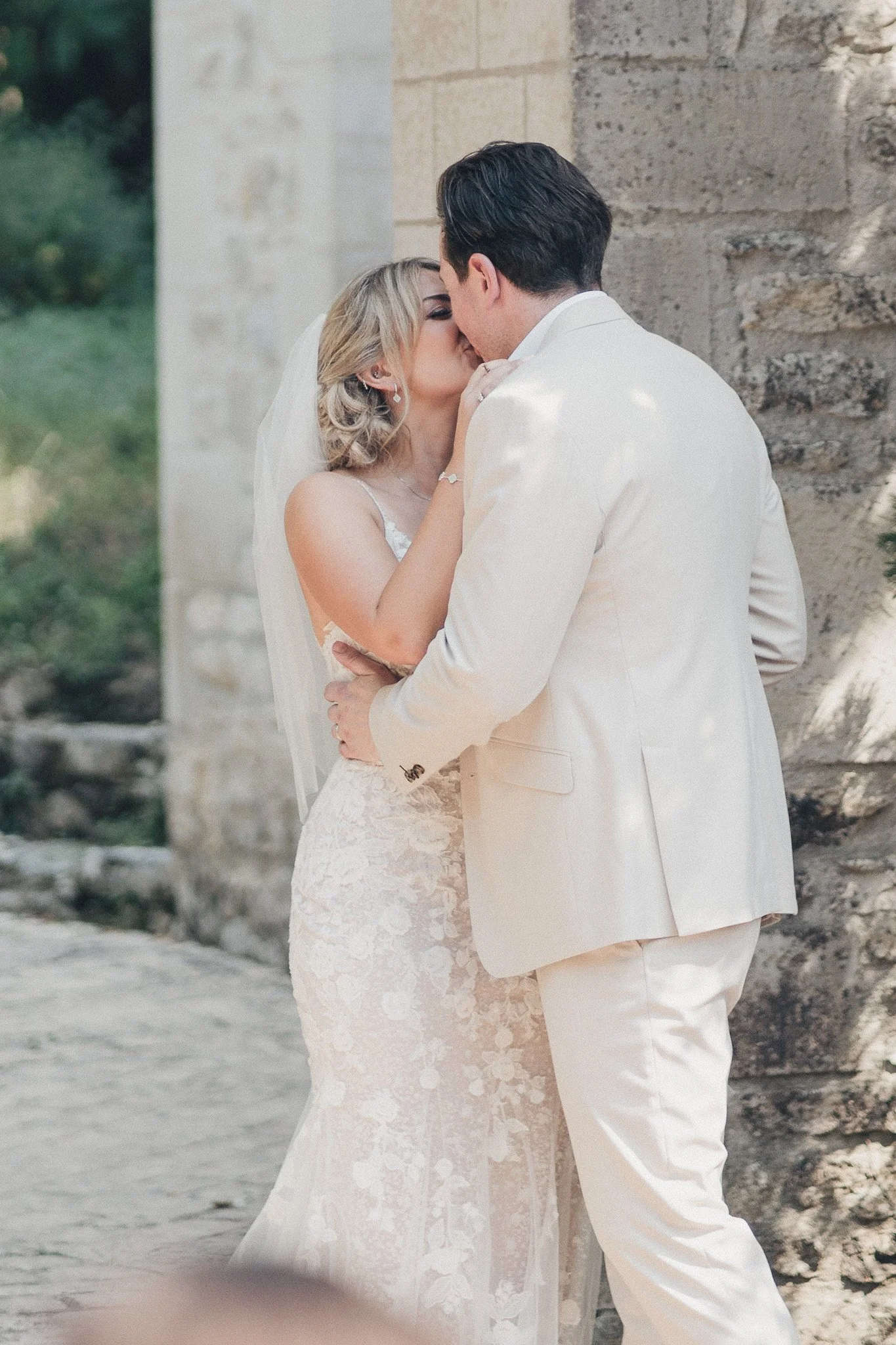 A close wedding portrait of the couple sharing the first kiss beside a stone wall at their Dordogne venue.