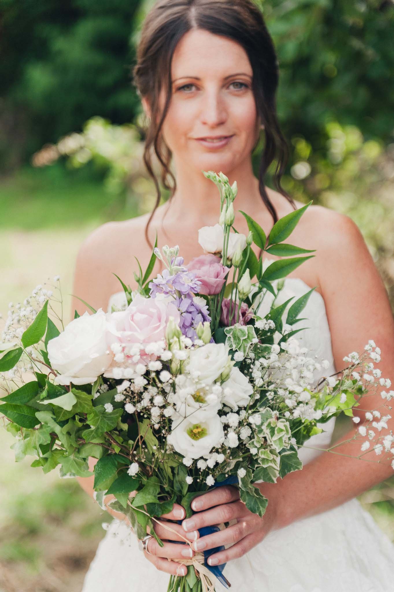 Close-up of the bride holding her bouquet outdoors before walking to the ceremony.