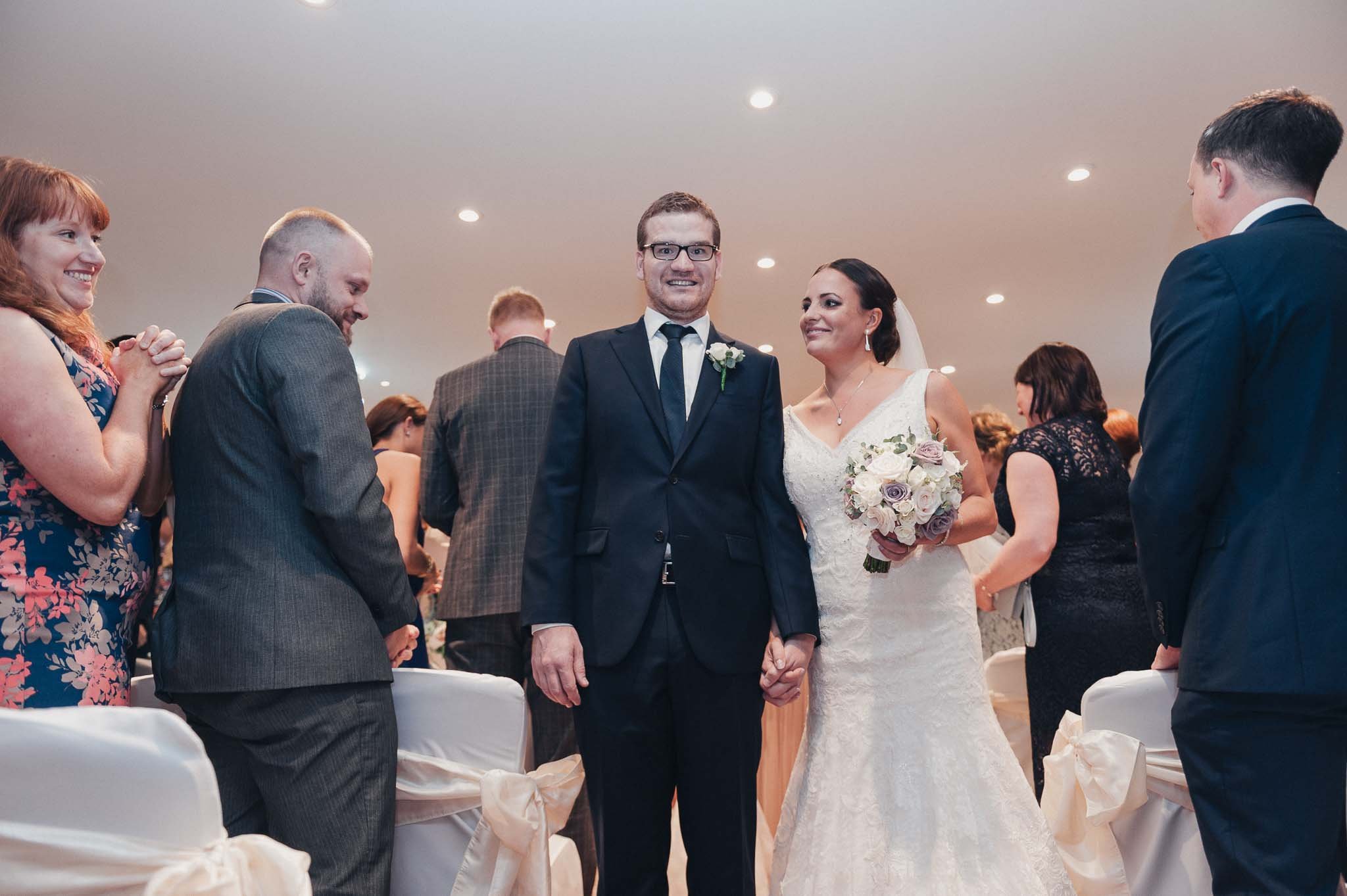 Bride and groom standing among their guests after the ceremony, sharing a relaxed moment together.
