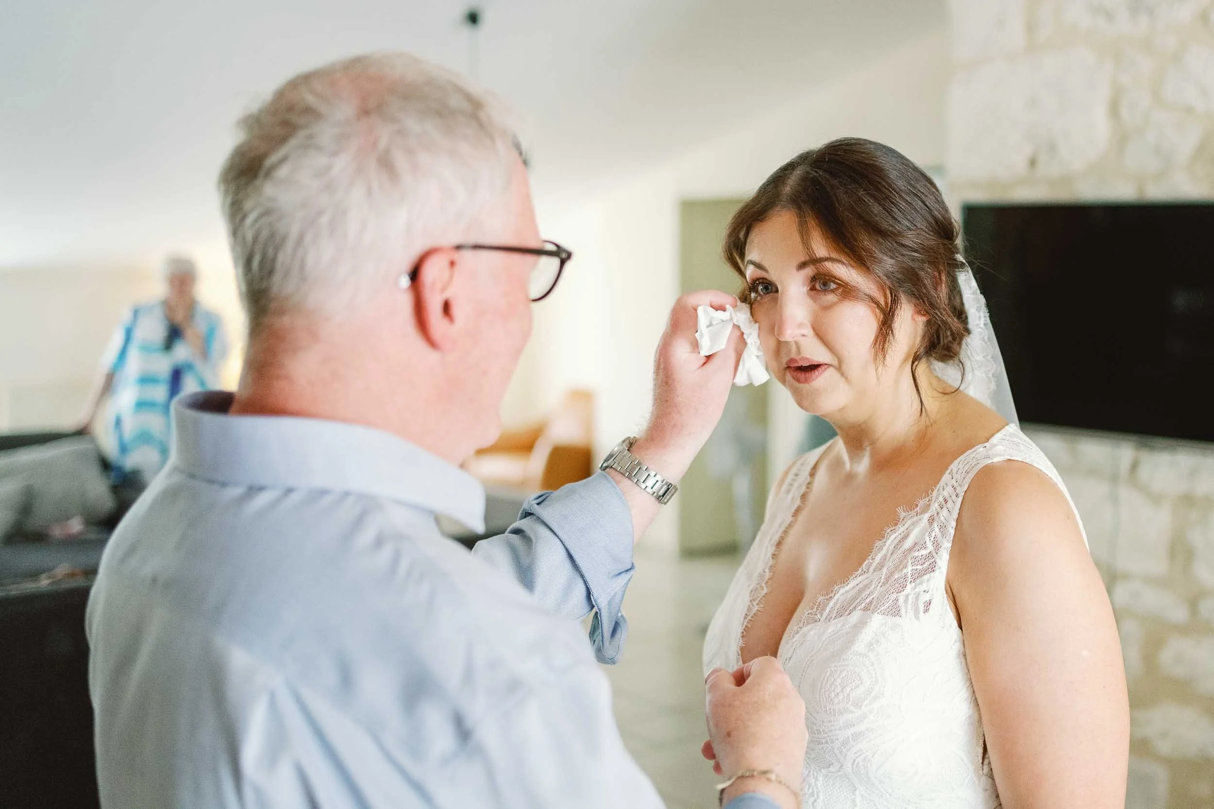 Bride's father wiping a tear from her cheek before the ceremony