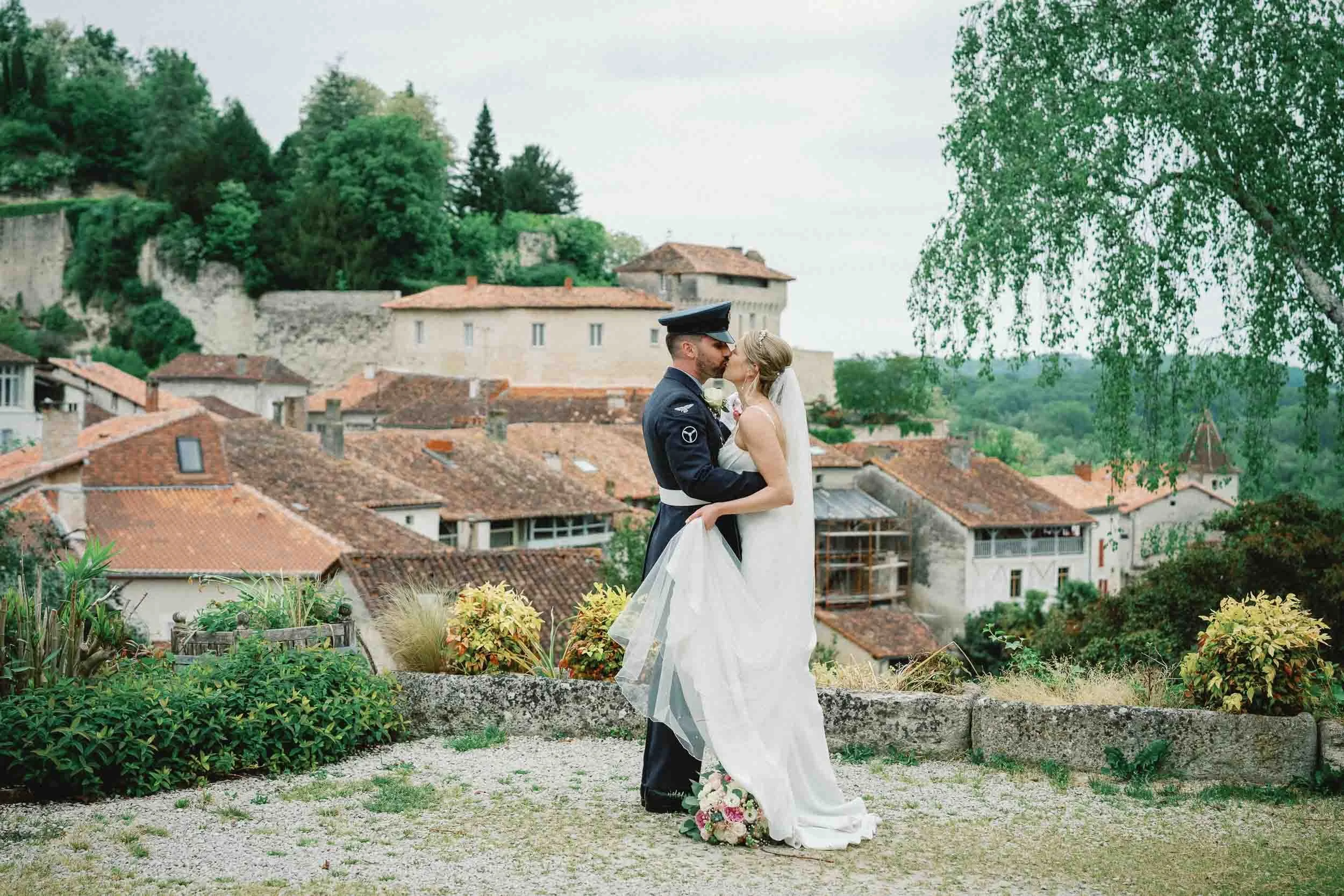 Bride and groom kissing overlooking the village of Aubeterre-sur-Dronne, Charente