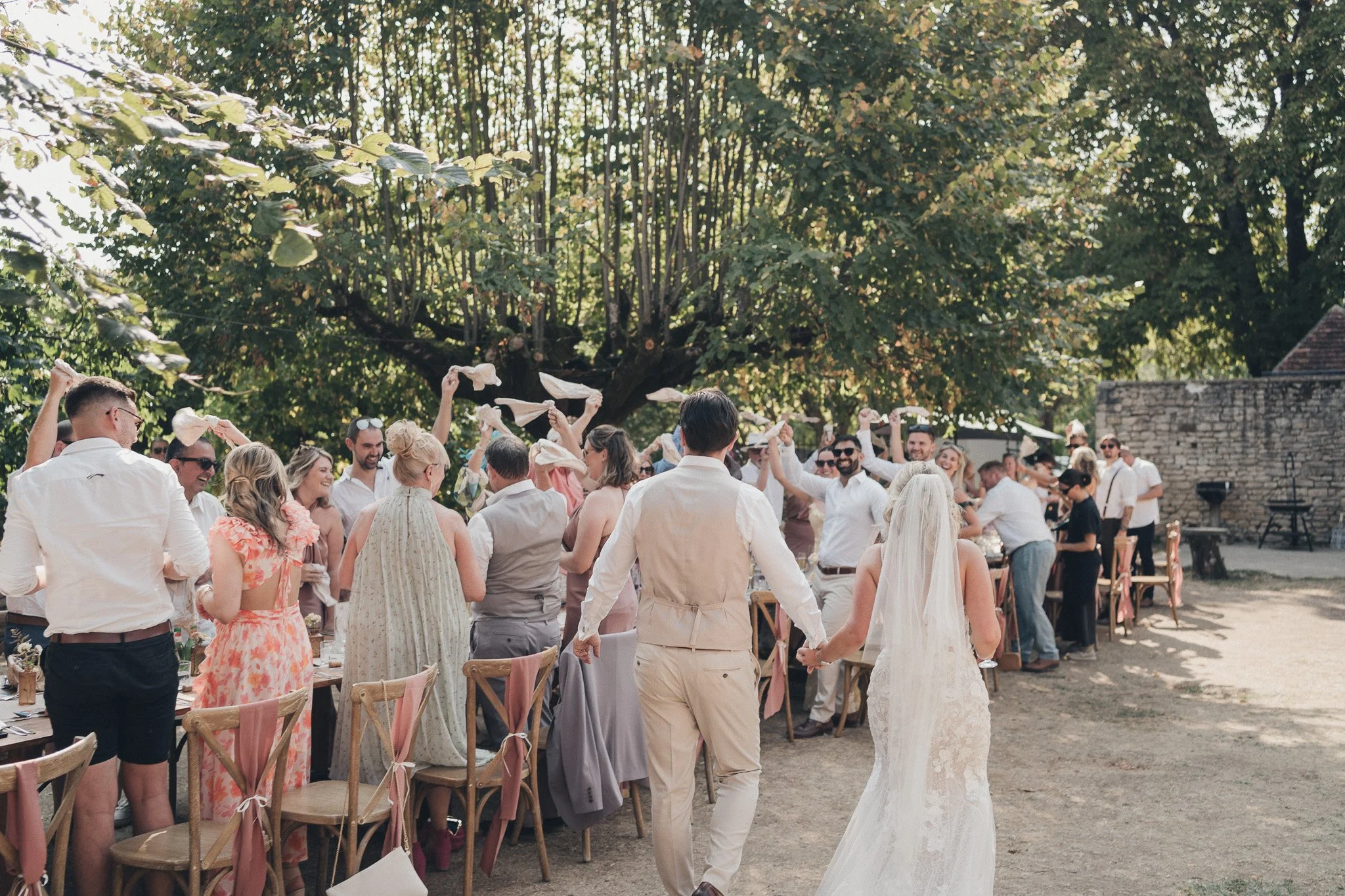 Guests standing and waving napkins during a joyful moment at the outdoor reception.