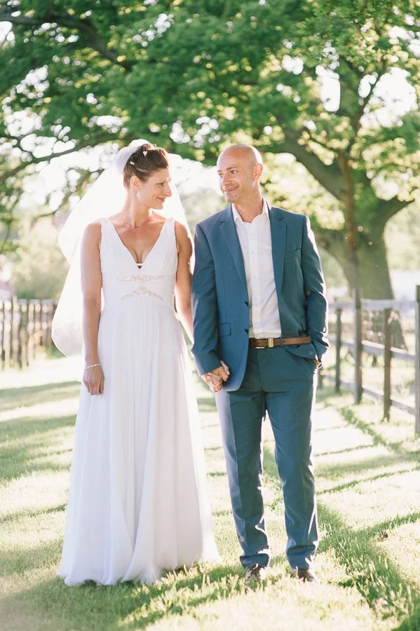 Bride and groom walking hand in hand in the shade of the trees after their ceremony in France.