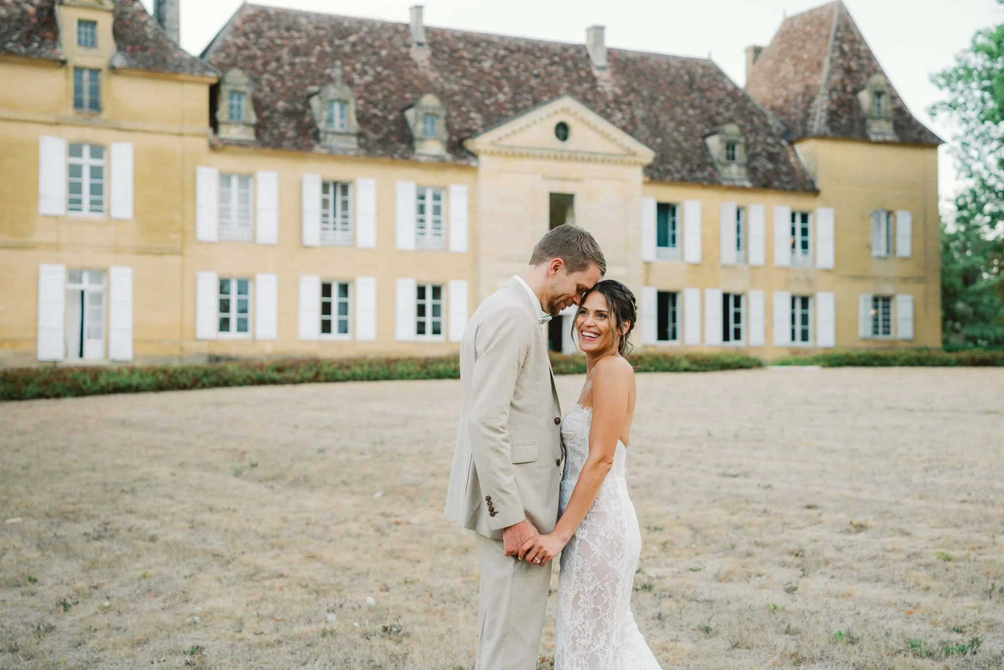 Bride and groom close together in front of Château de Sainte Croix, Dordogne