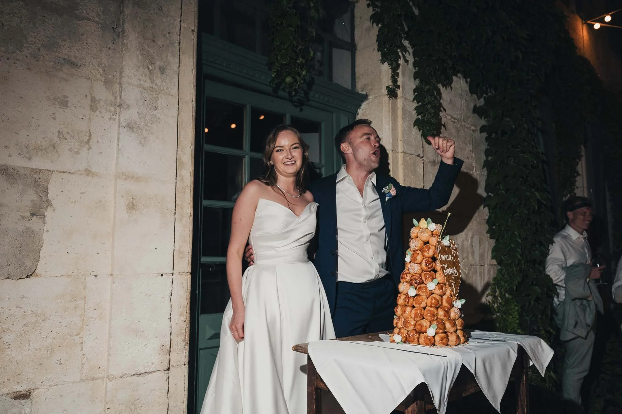 Bride and groom smiling beside their croquembouche before cutting the cake.