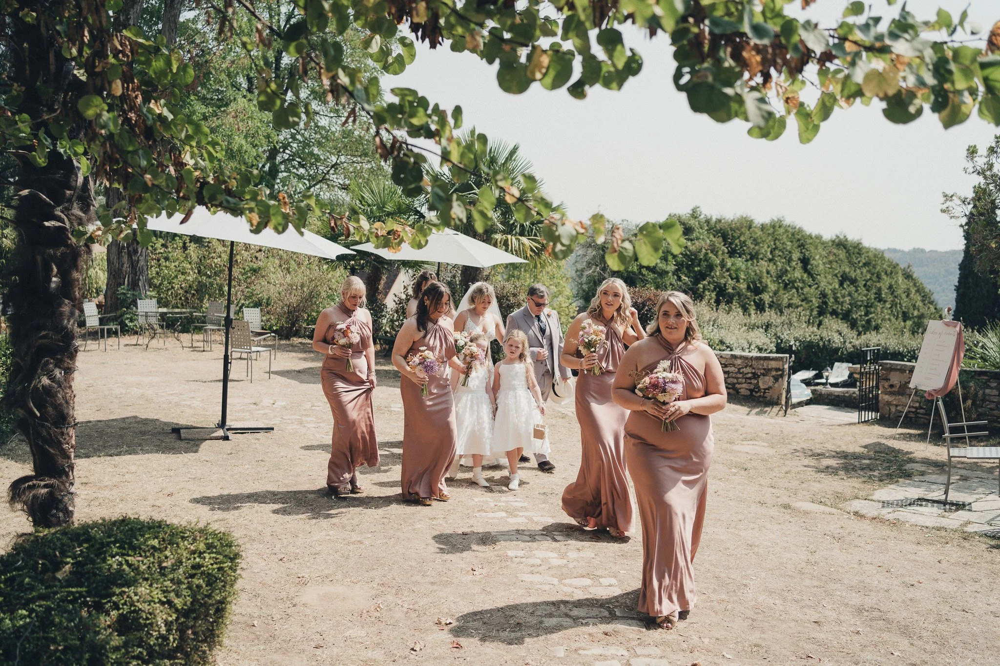 Bridesmaids walking toward the outdoor ceremony space at the château.